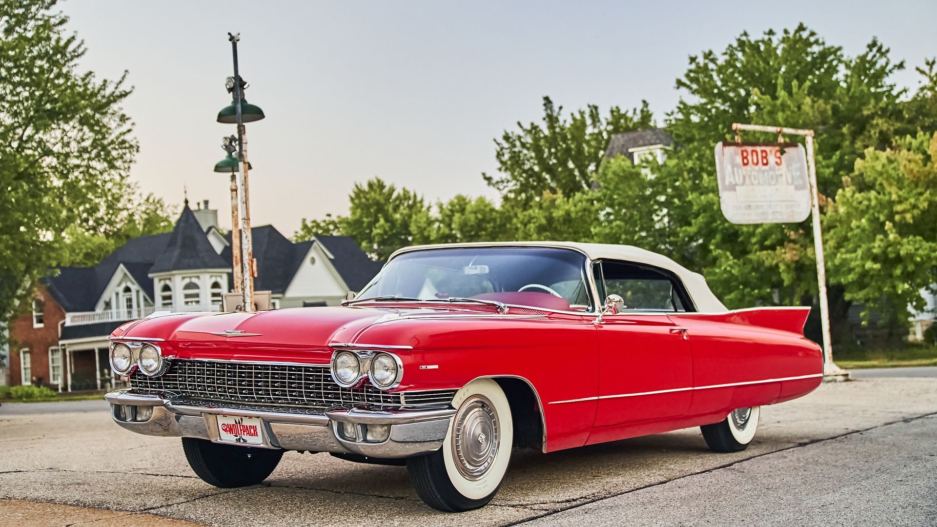 A red cadillac is parked on the side of the road