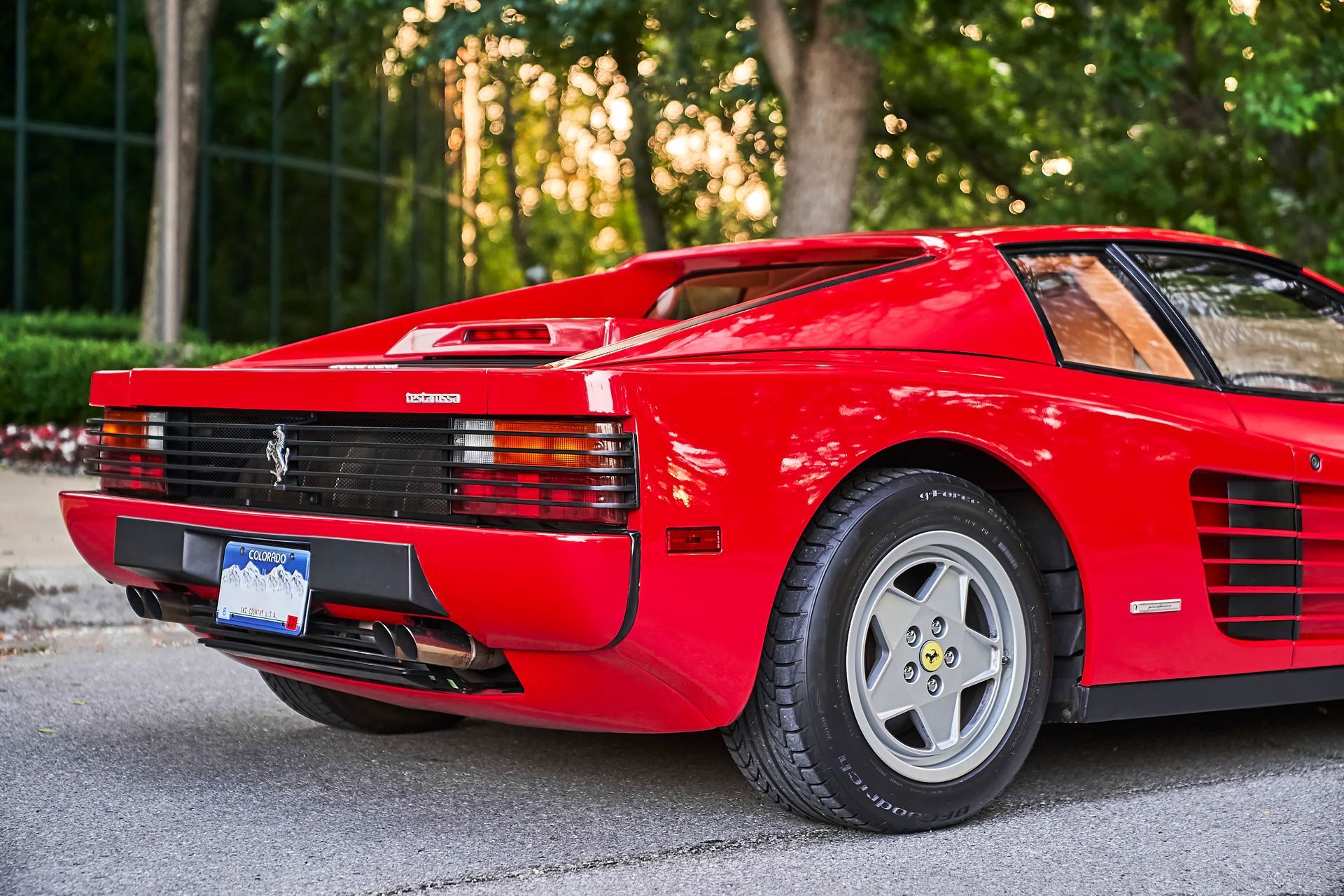 A red ferrari testarossa is parked on the side of the road.