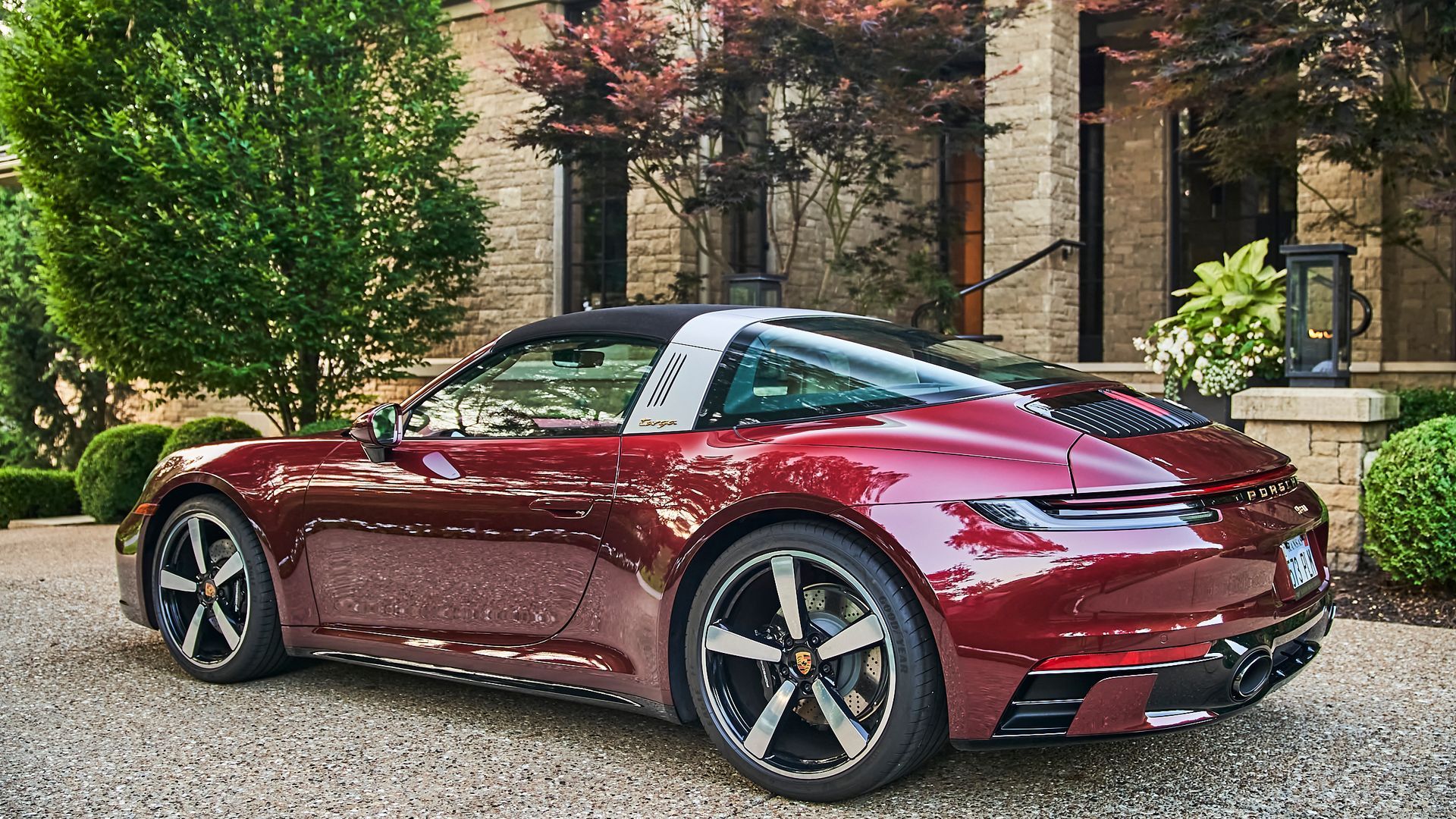 A red porsche targa is parked in front of a house.