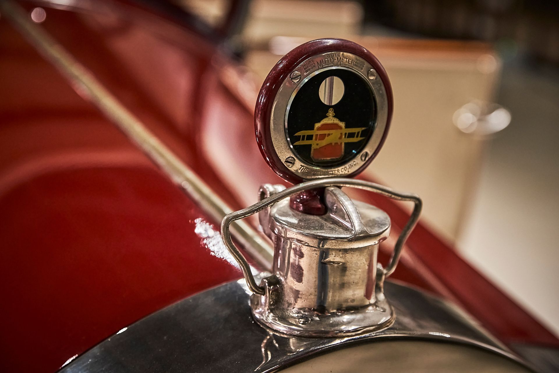 A close up of a car hood ornament on a red car.