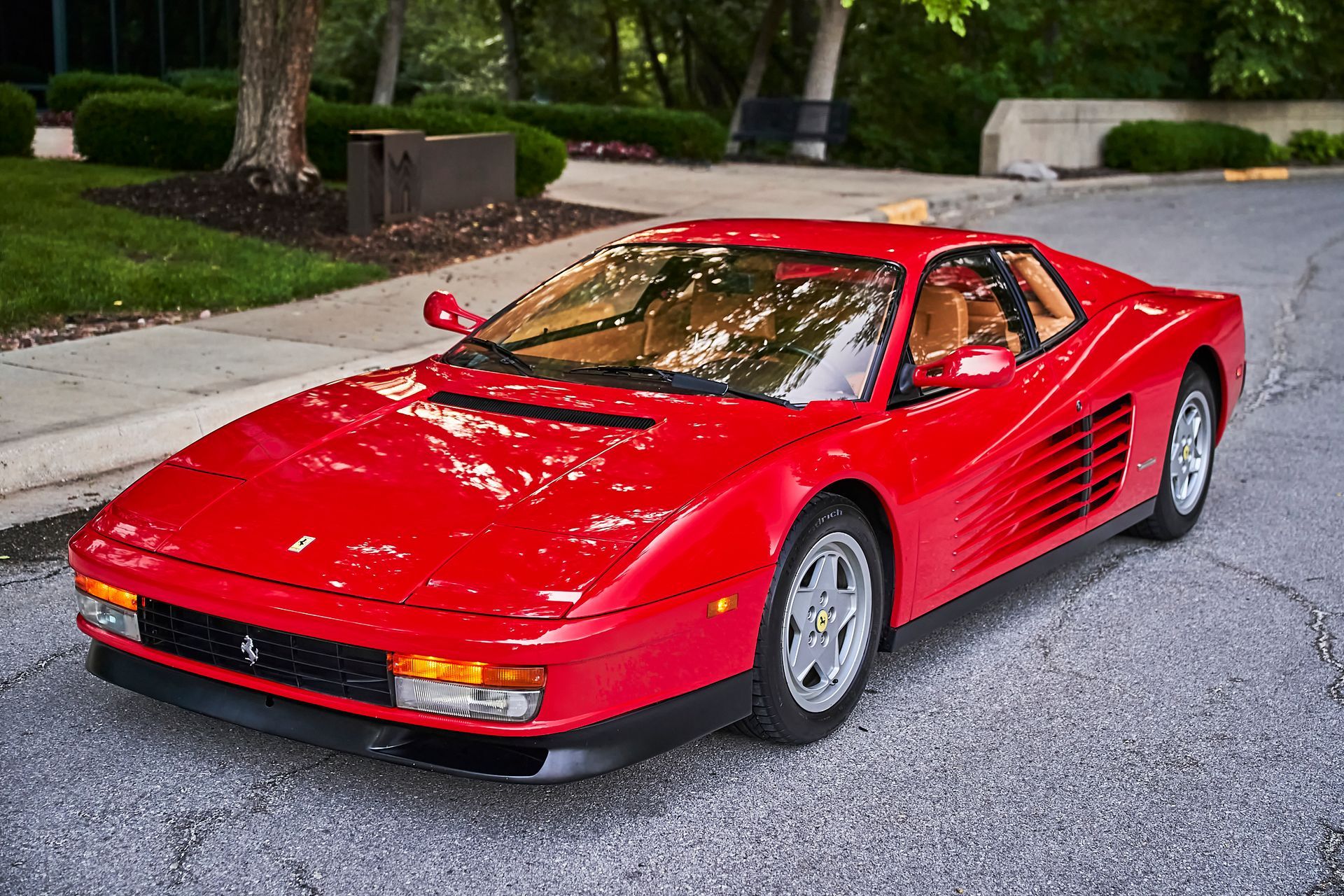 A red ferrari testarossa is parked on the side of the road.