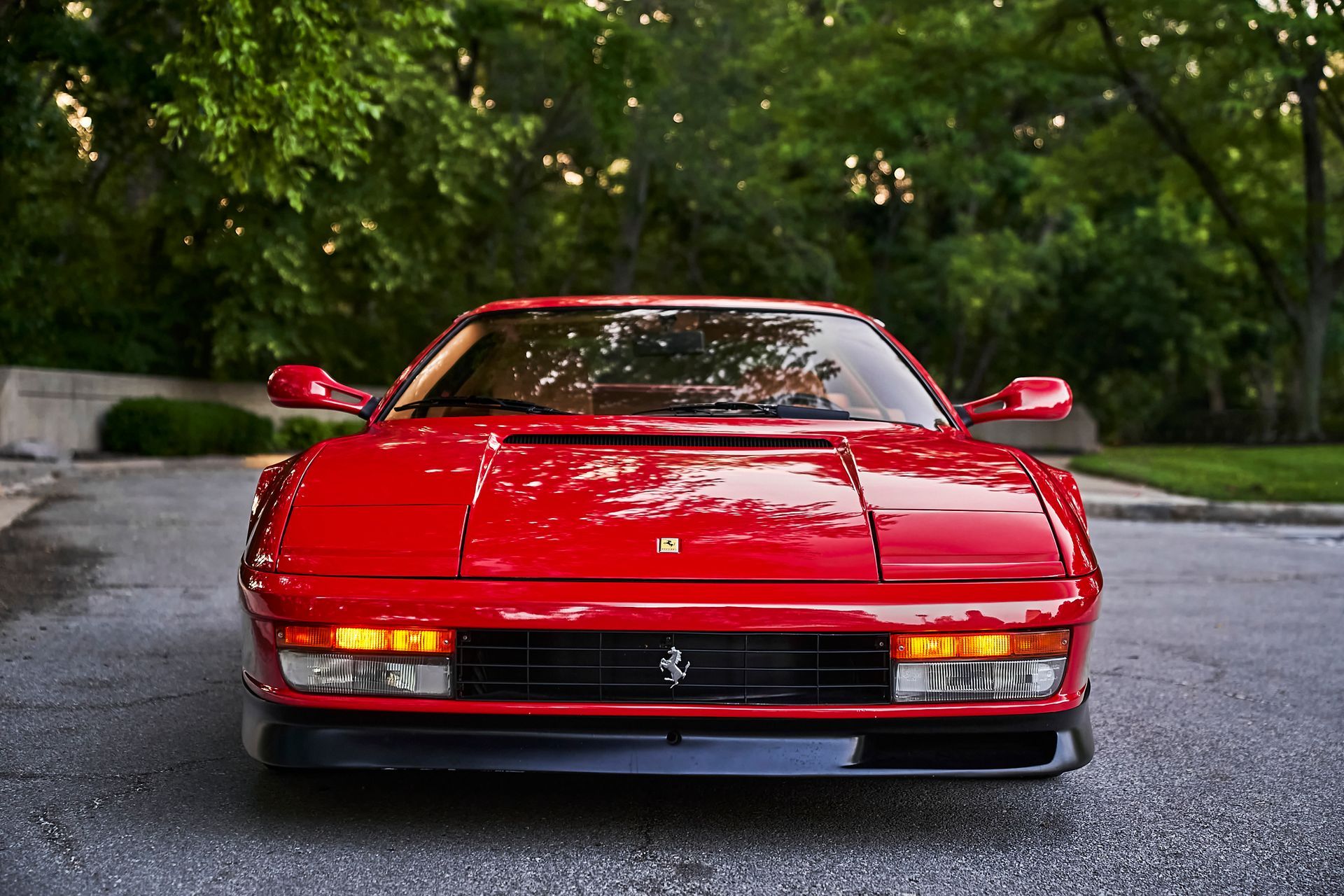 A red ferrari is parked on the side of the road.