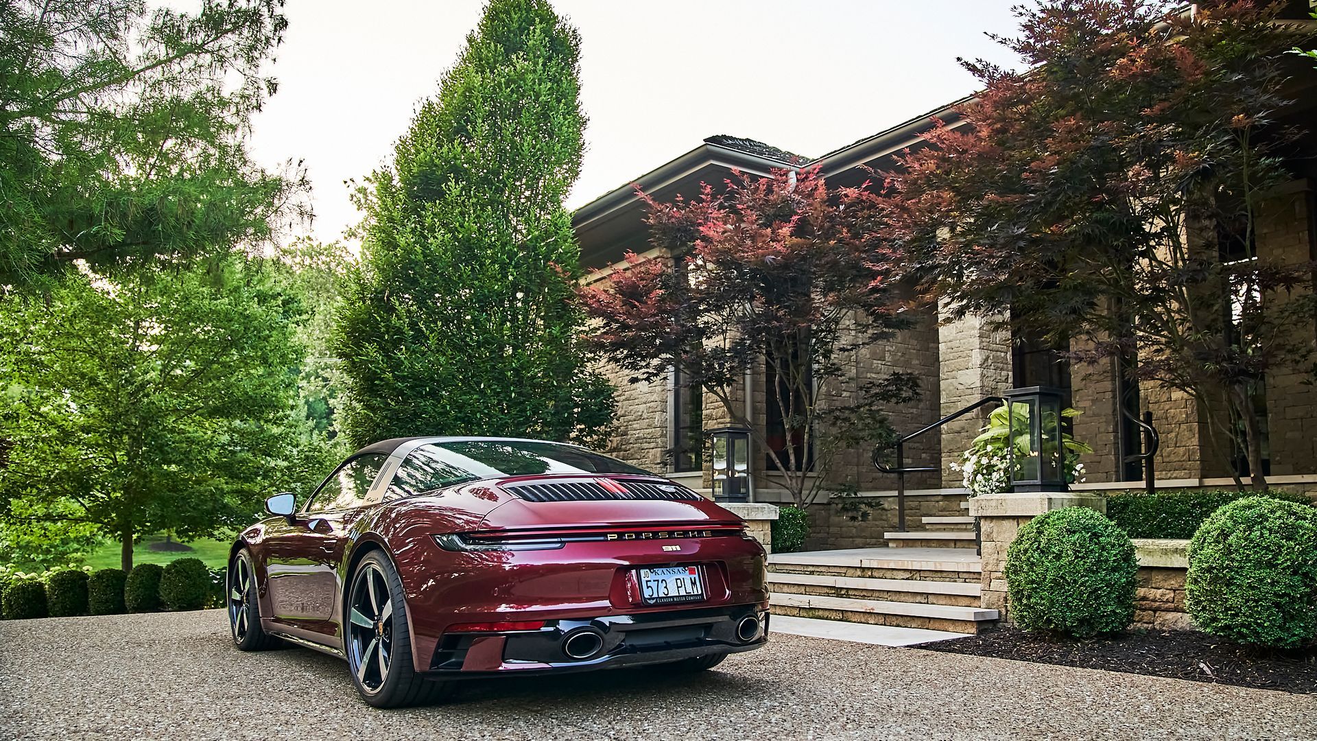 A red sports car is parked in front of a large house.