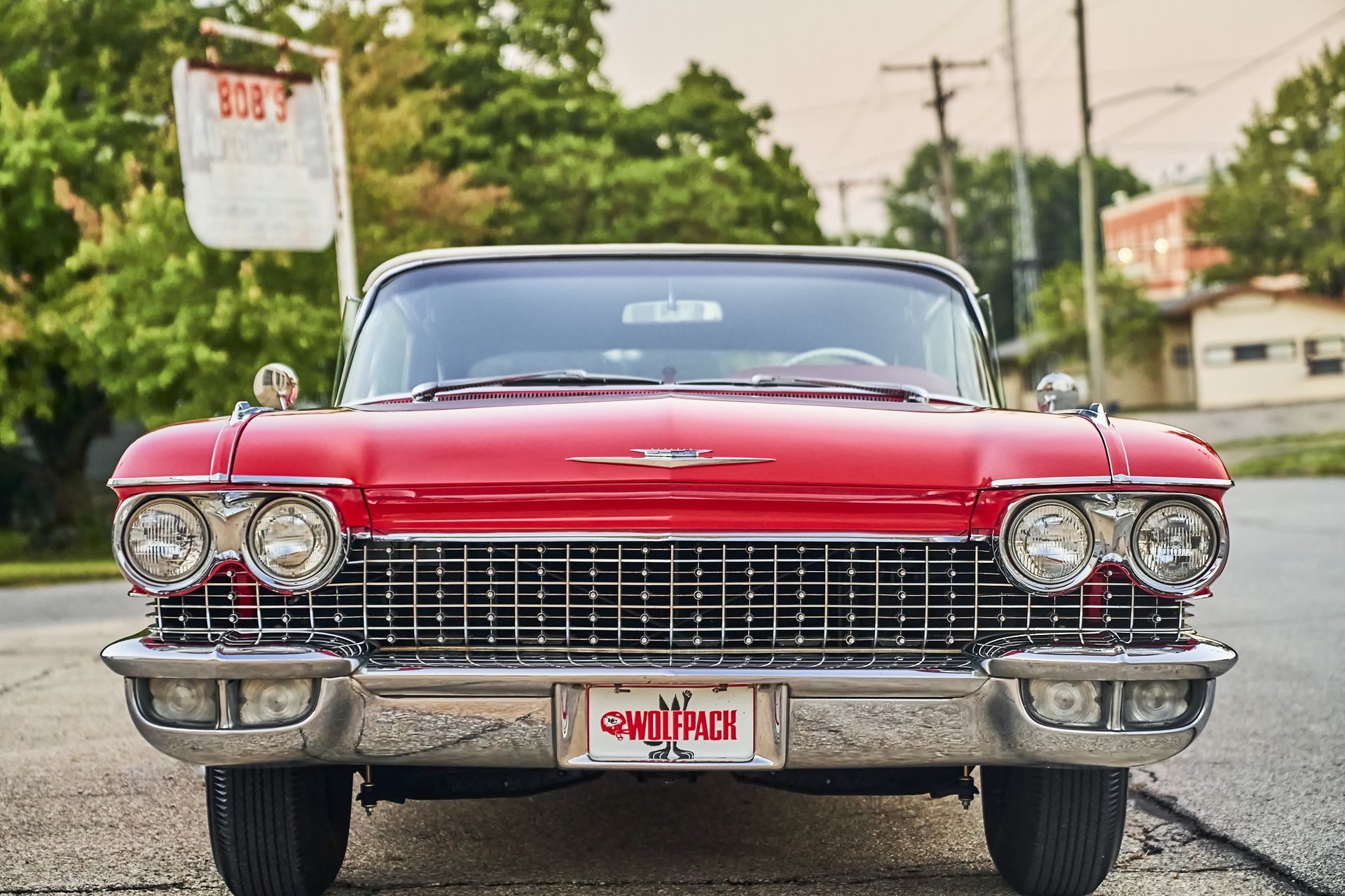 A red cadillac is parked on the side of the road