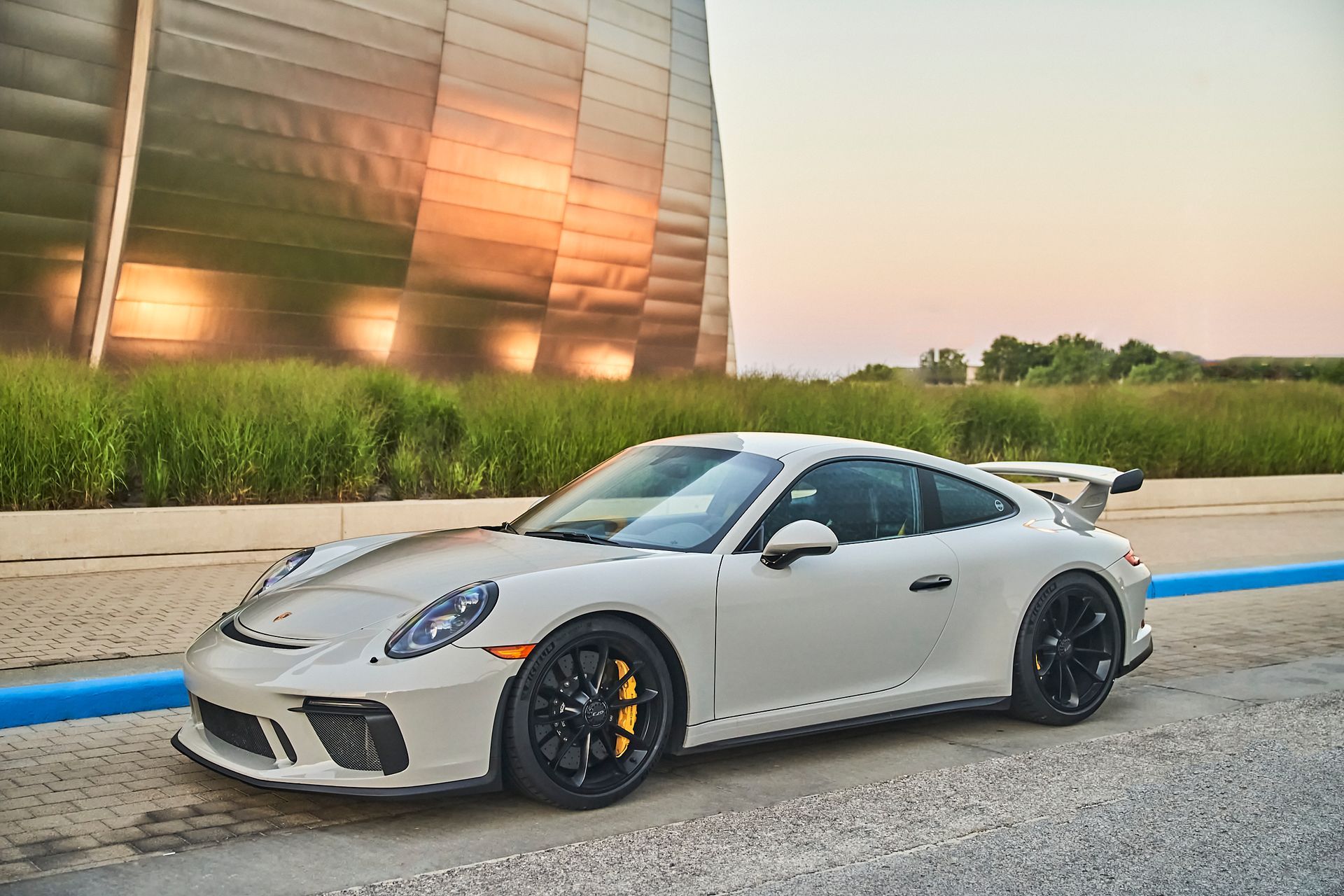 A white porsche 911 gt3 is parked in front of a building.