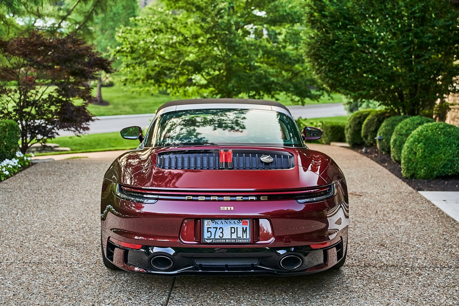 A red sports car is parked on a gravel driveway.