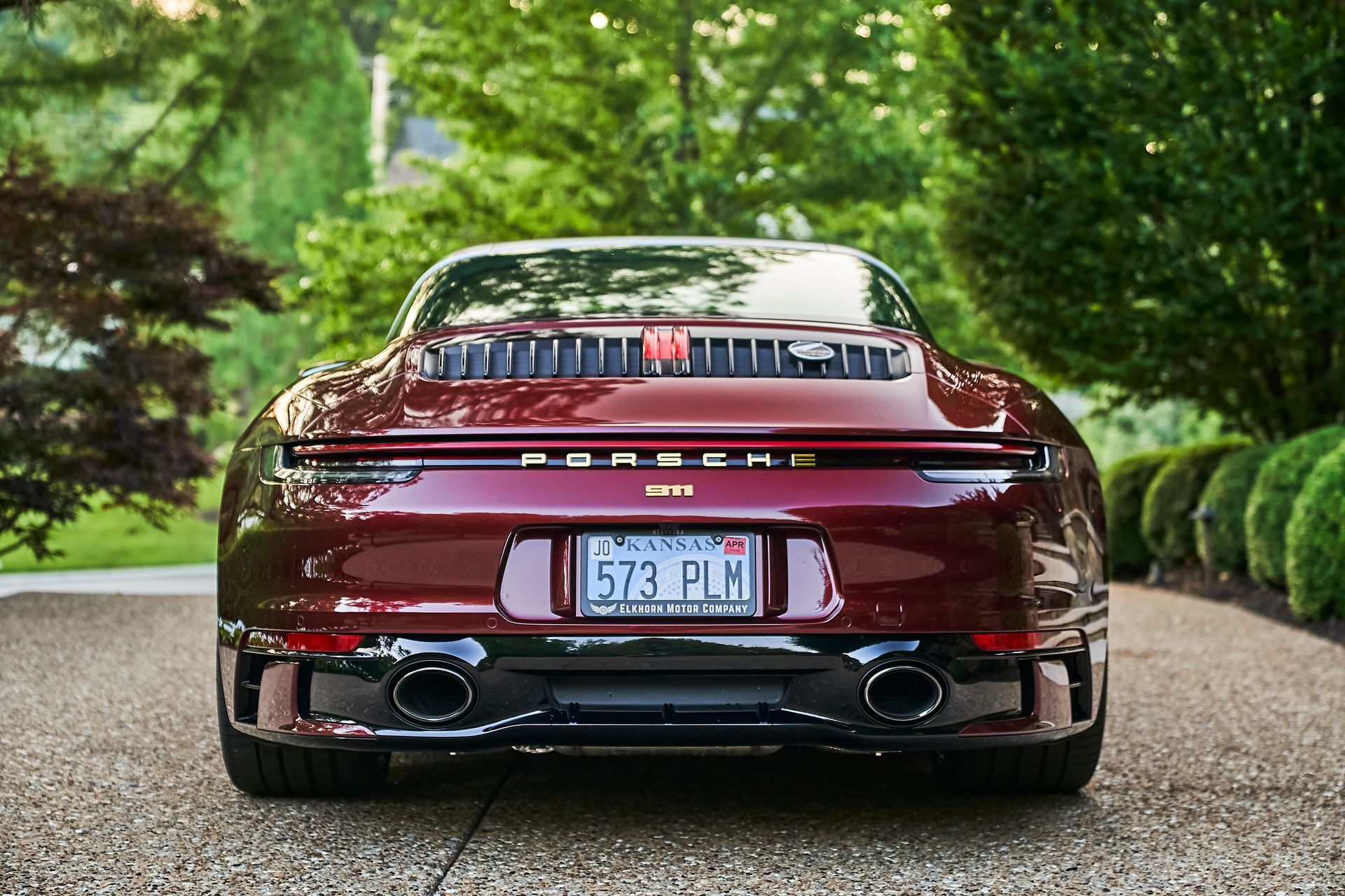 A red porsche 911 targa is parked in a driveway.