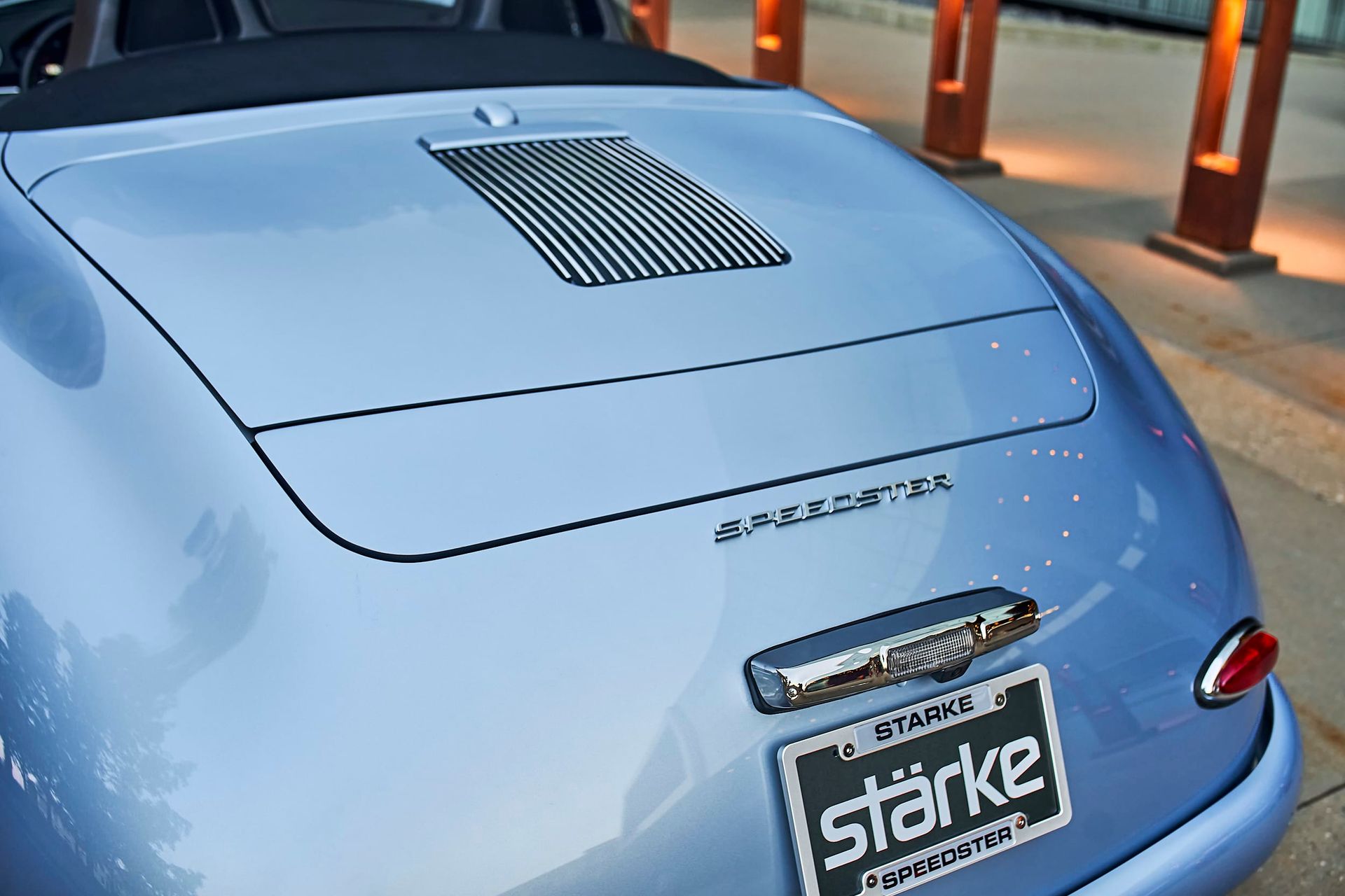 Light blue classic Porsche convertible, rear view, with a Stark license plate, parked outside.