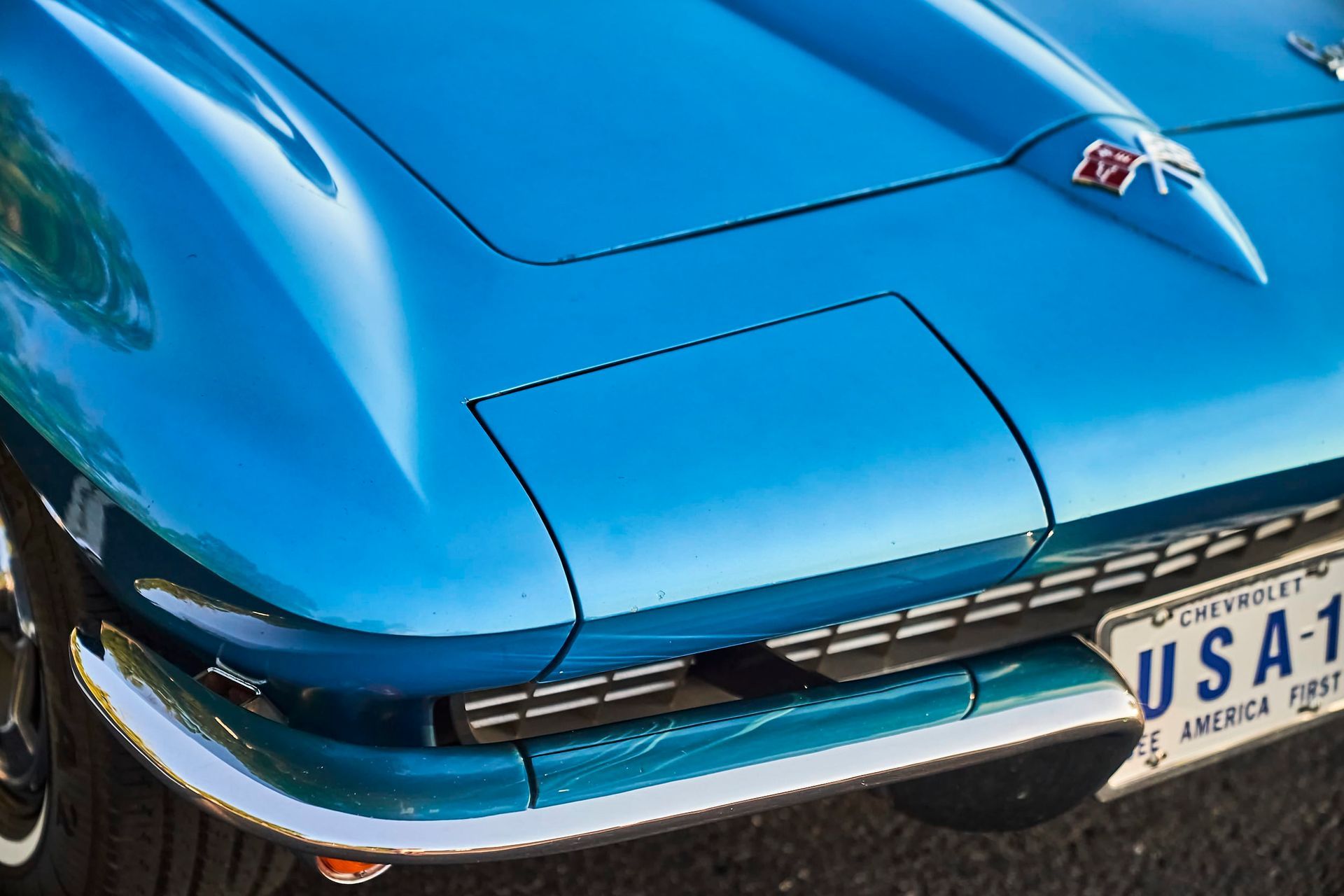 Blue classic Corvette car hood and front end with chrome trim and license plate.