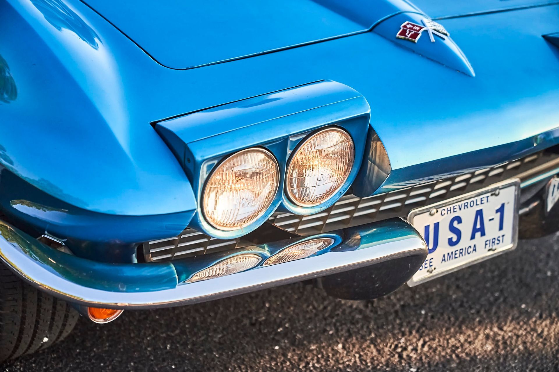 Blue vintage Corvette front, with headlights illuminated and USA-1 license plate.