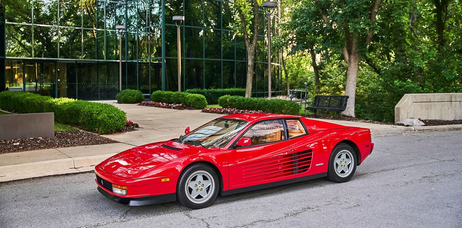 A red sports car is parked on the side of the road in front of a building.