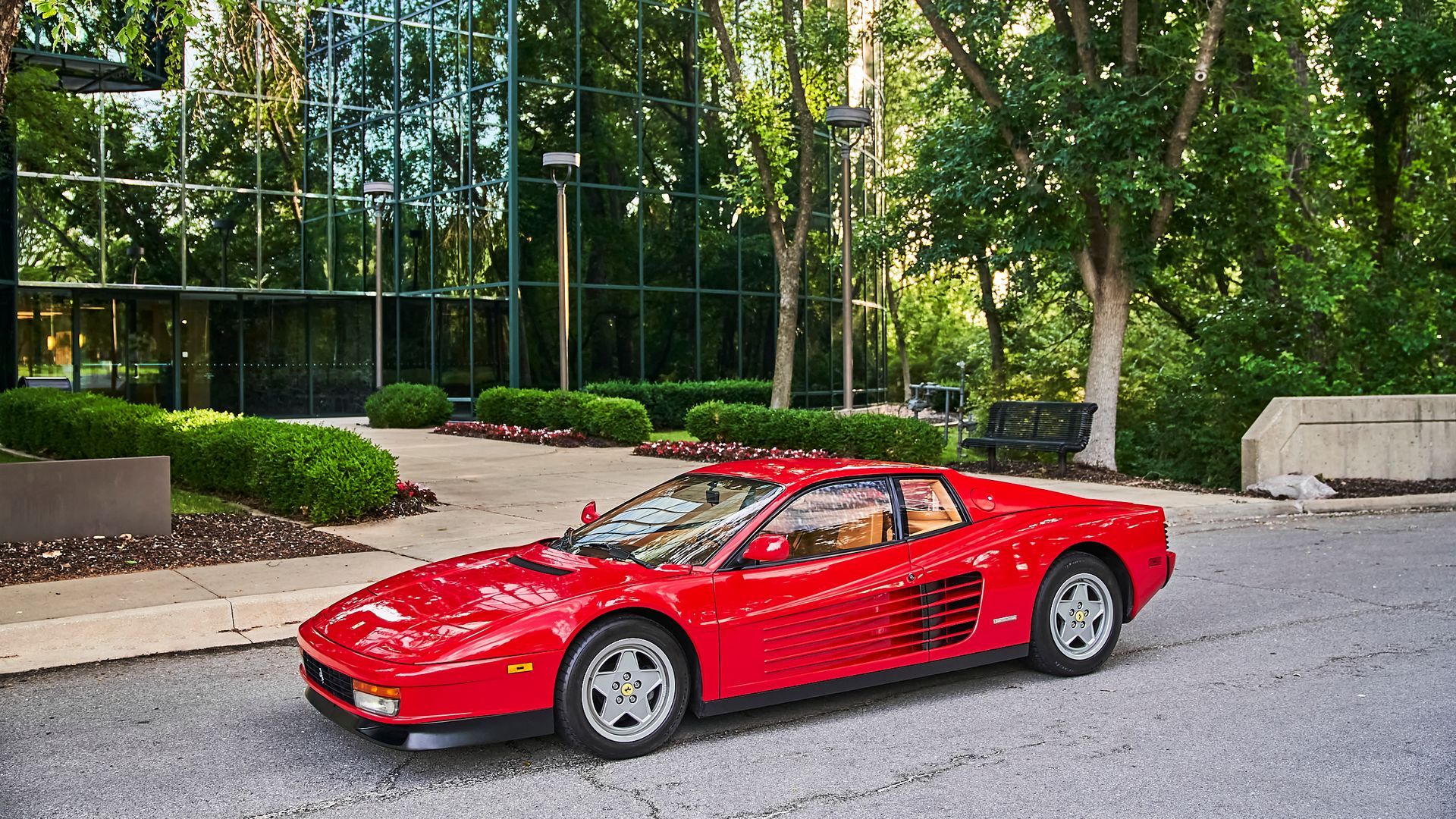 A red sports car is parked on the side of the road in front of a building.