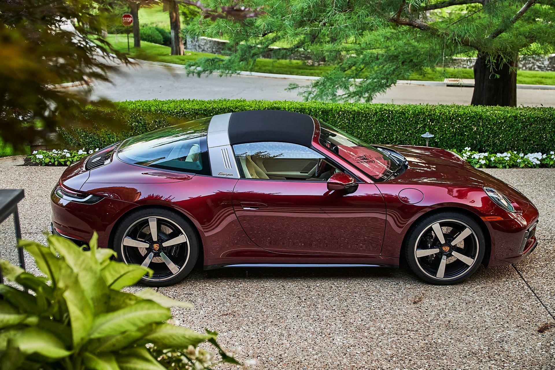 A red porsche targa is parked in a gravel driveway.