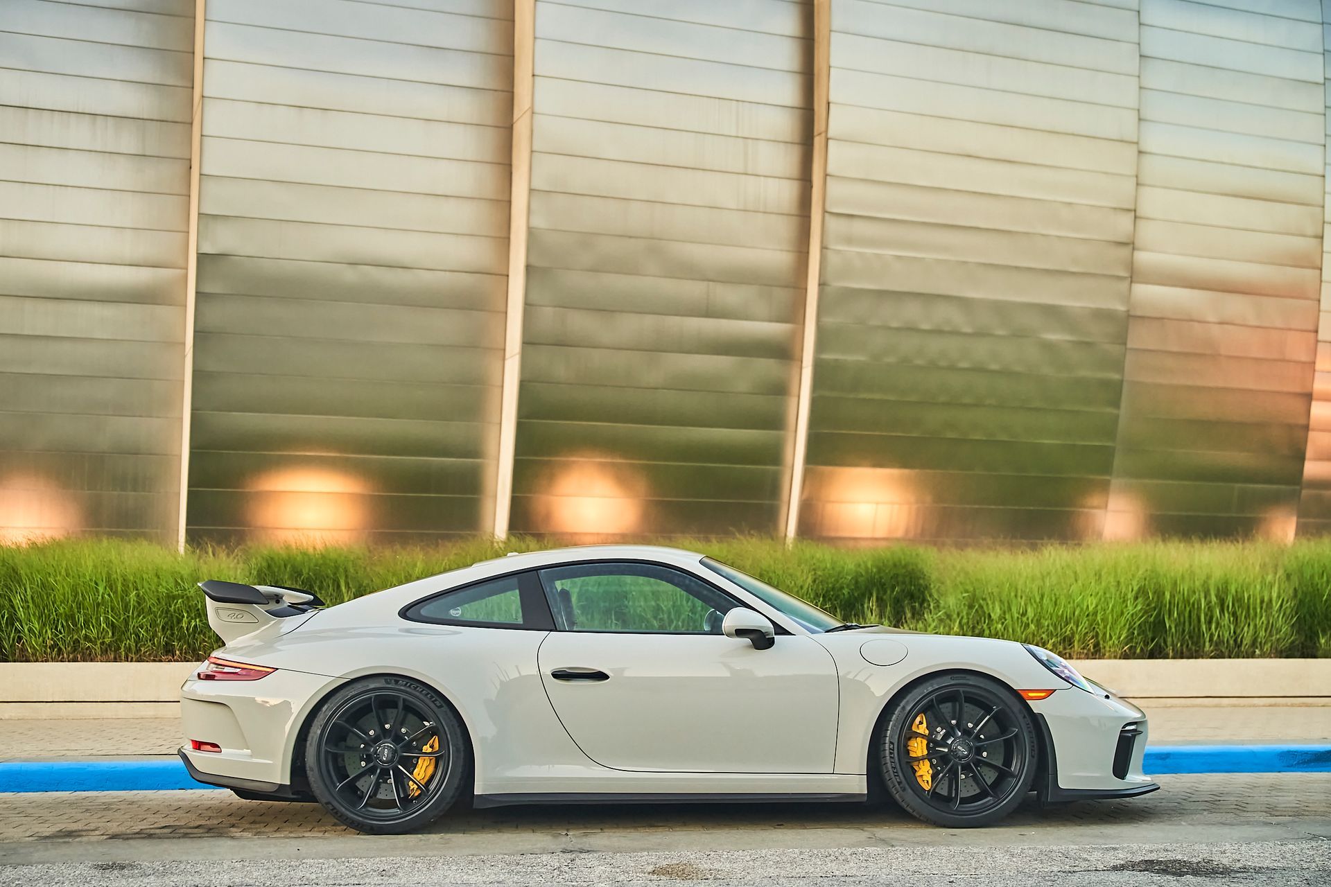 A white porsche 911 gt3 rs is parked in front of a building.