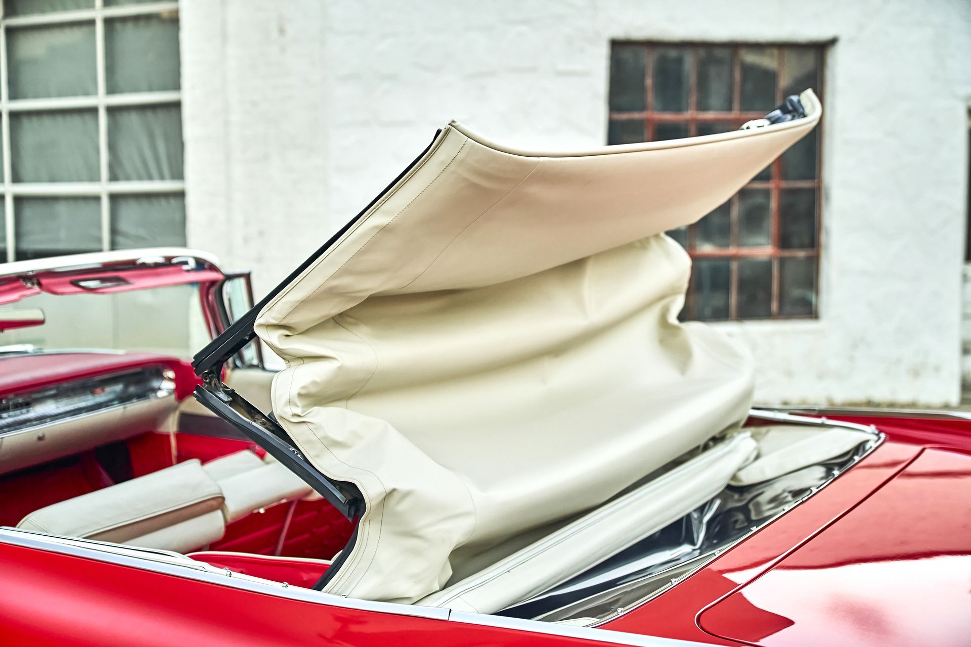 The roof of a red car with the sunroof open.