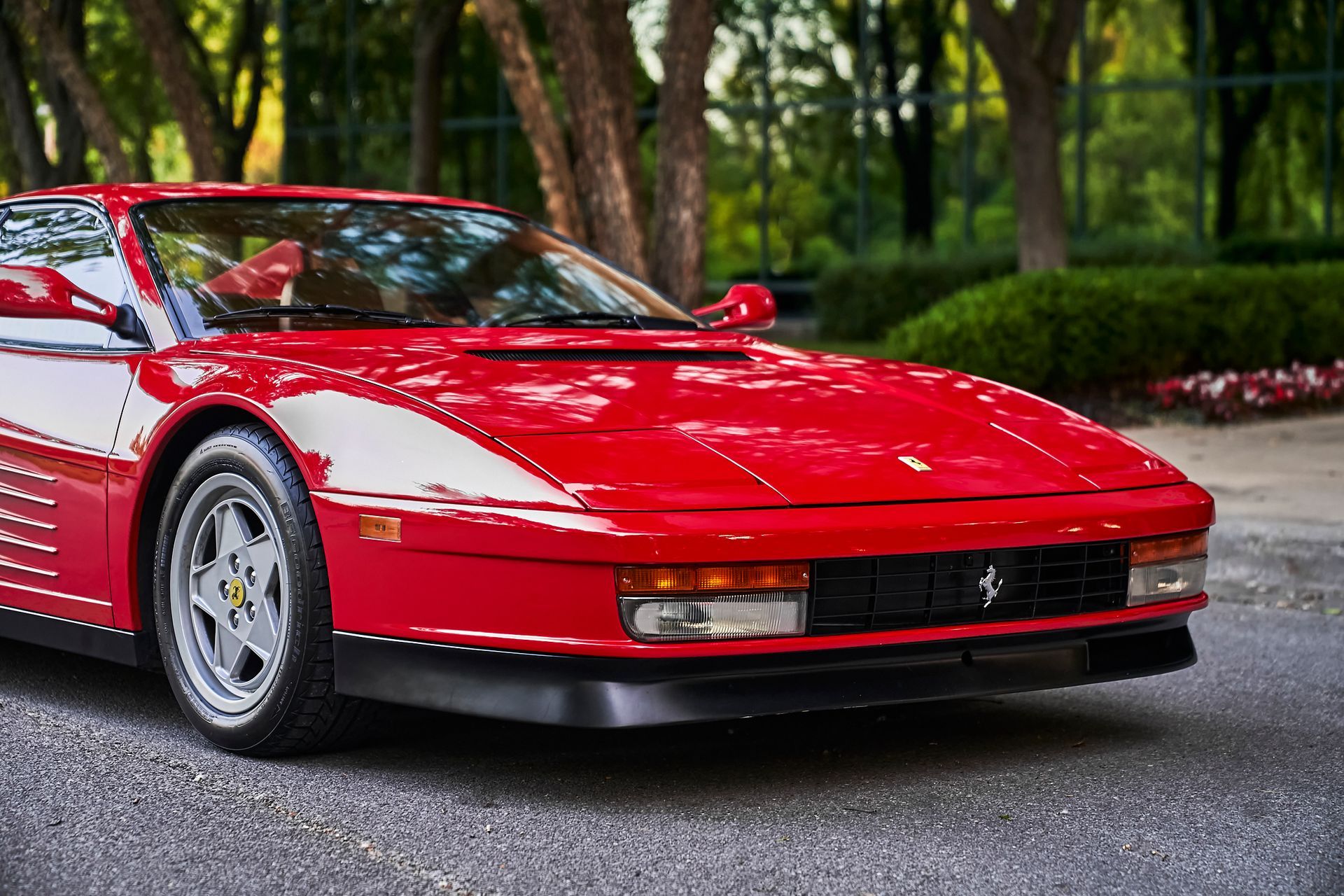 A red ferrari testarossa is parked on the side of the road.