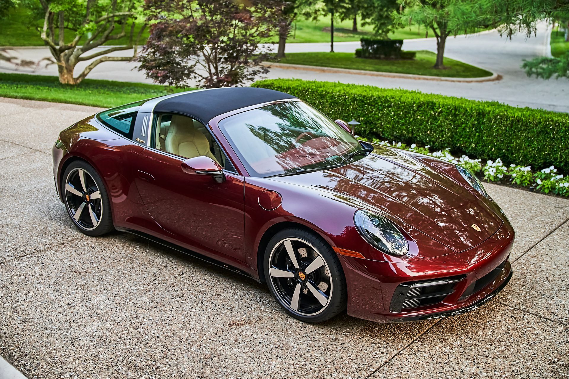 A red porsche targa is parked in a driveway.