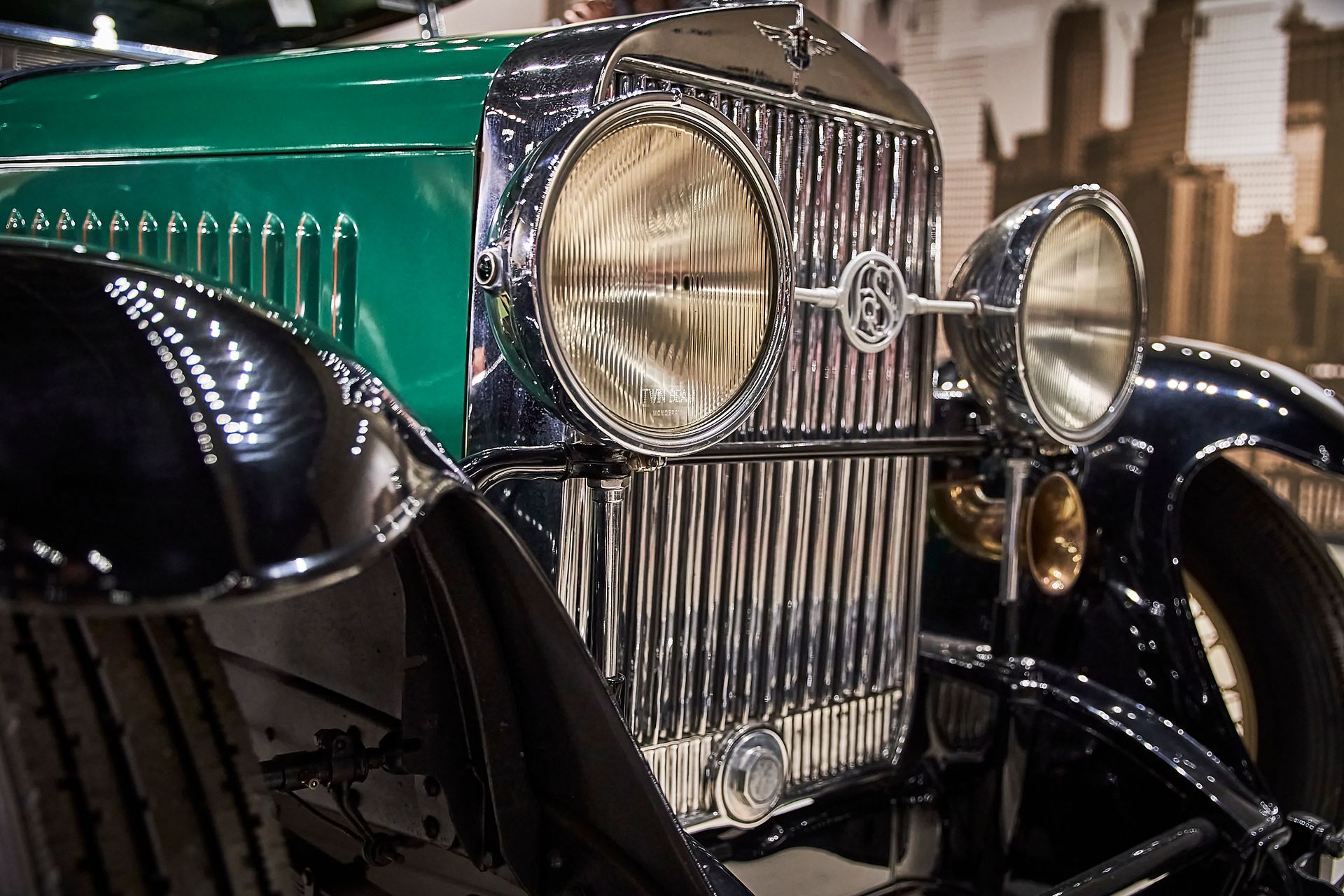 A close up of the front of a green and black vintage car.