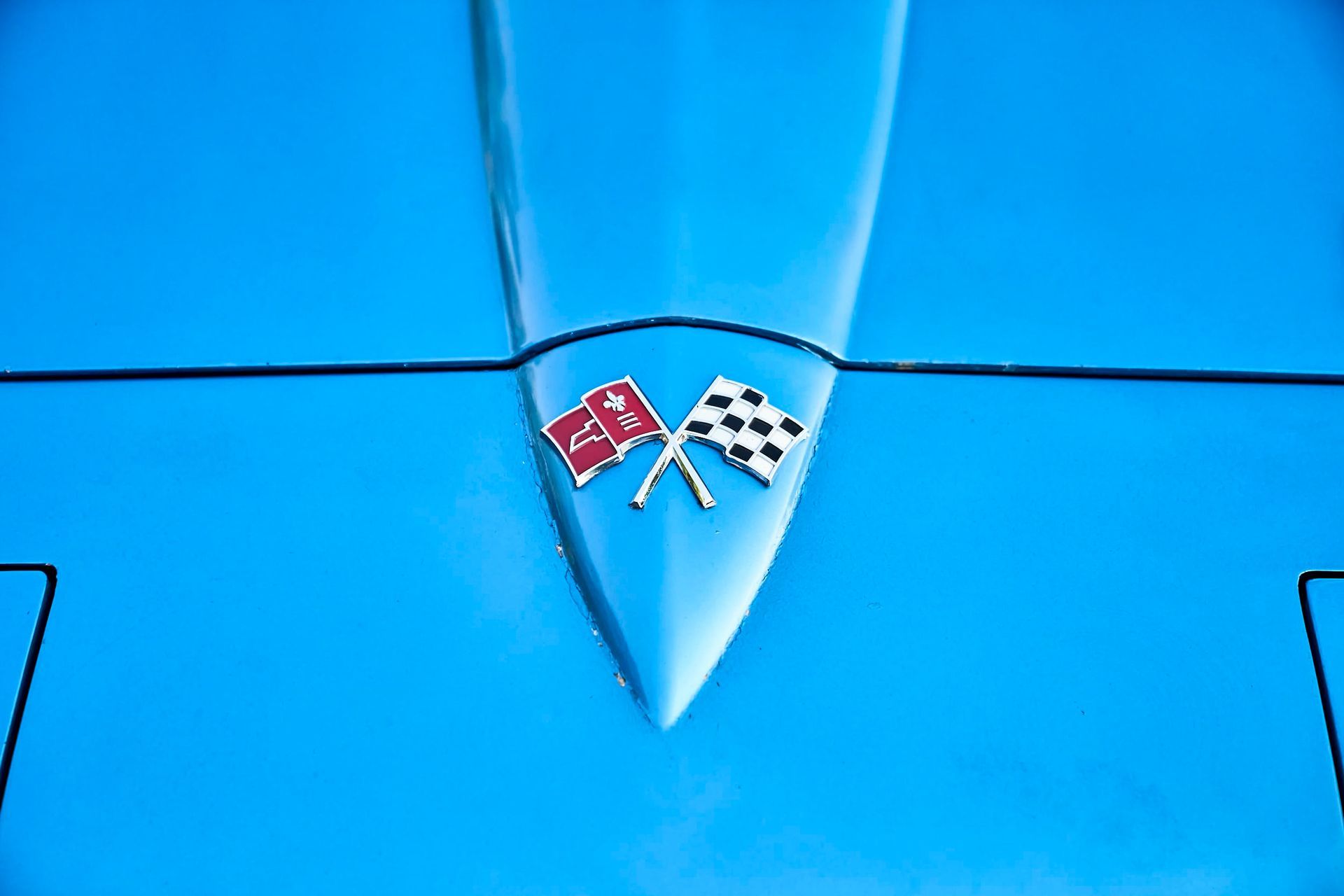 Blue Corvette hood with crossed flags emblem.