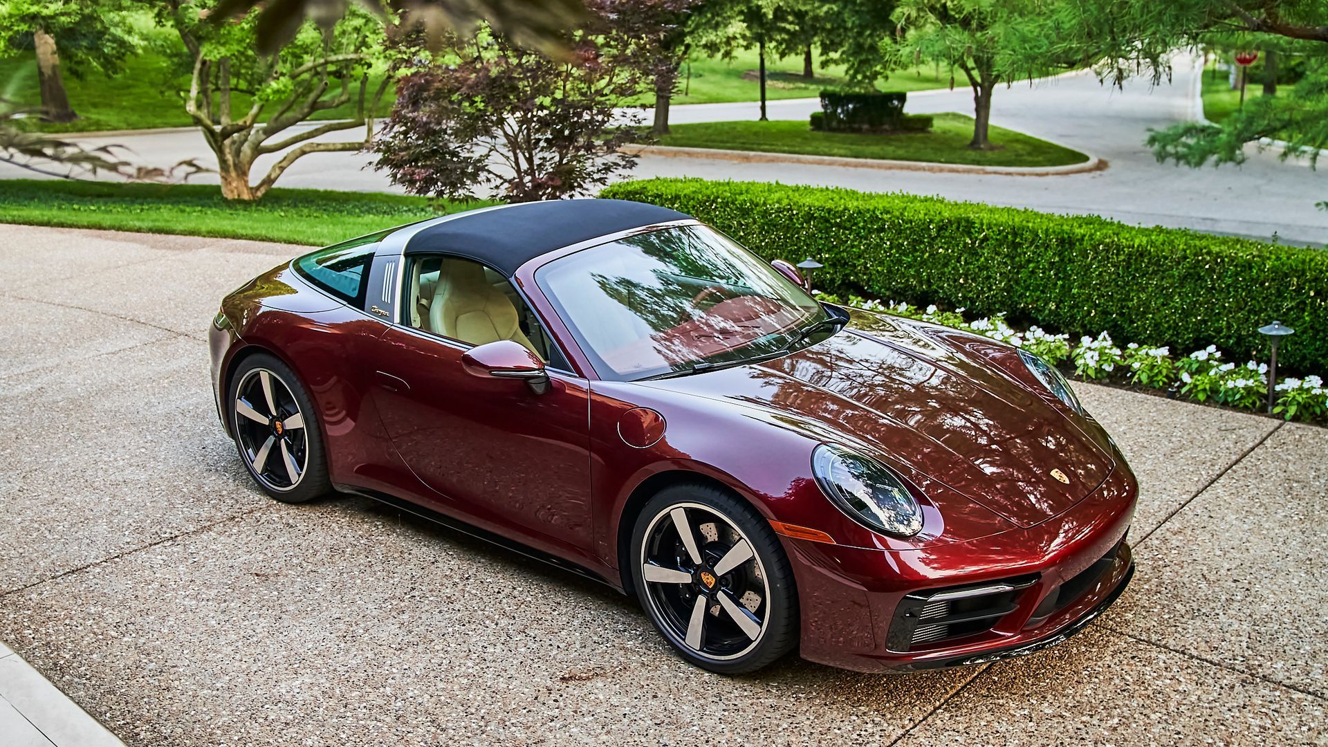 A red porsche targa is parked in a driveway.