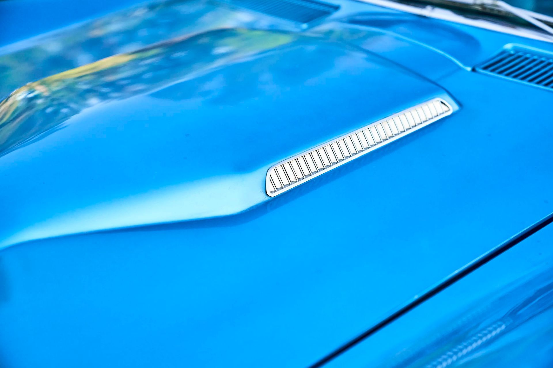 Blue car hood with a silver air vent.