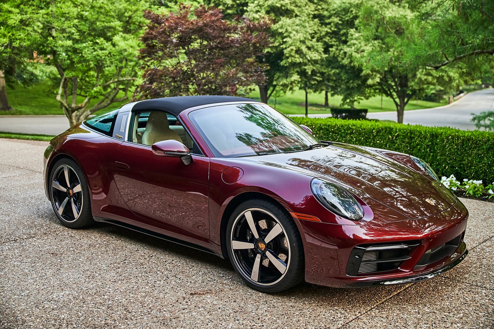 A red porsche targa is parked in a gravel driveway.