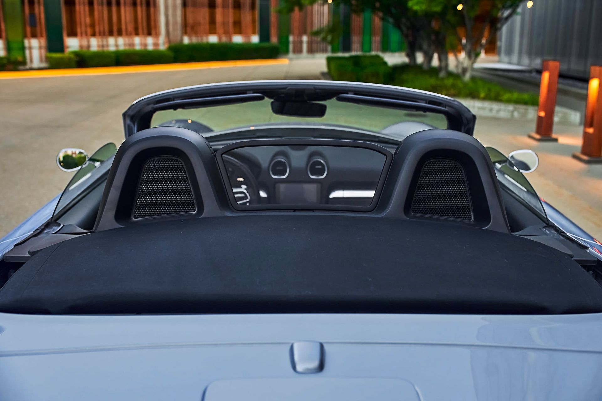 A close-up of the interior of a blue convertible car, showing the dashboard and black seats with a partially open top.