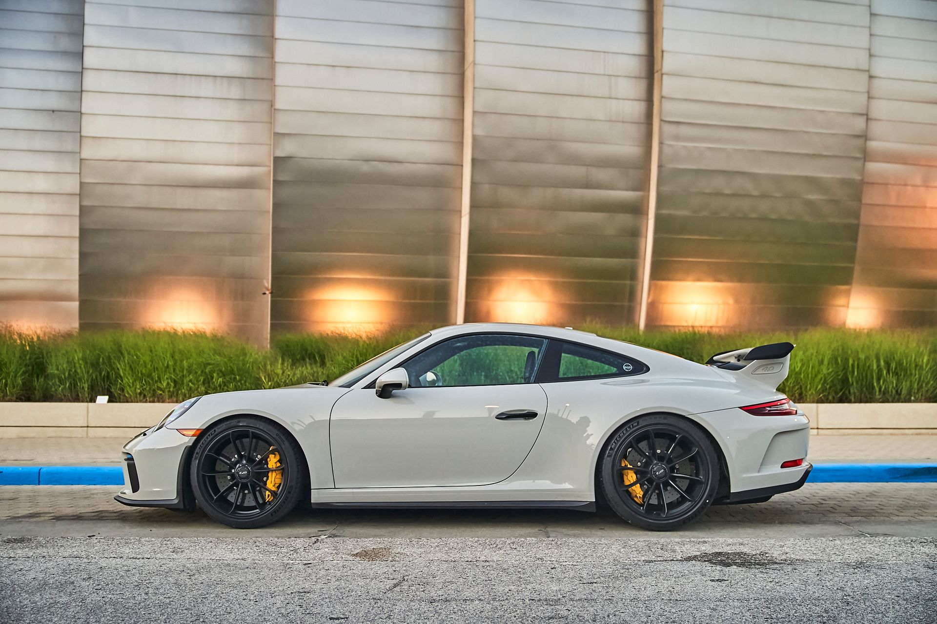 A white porsche 911 gt3 is parked in front of a building.