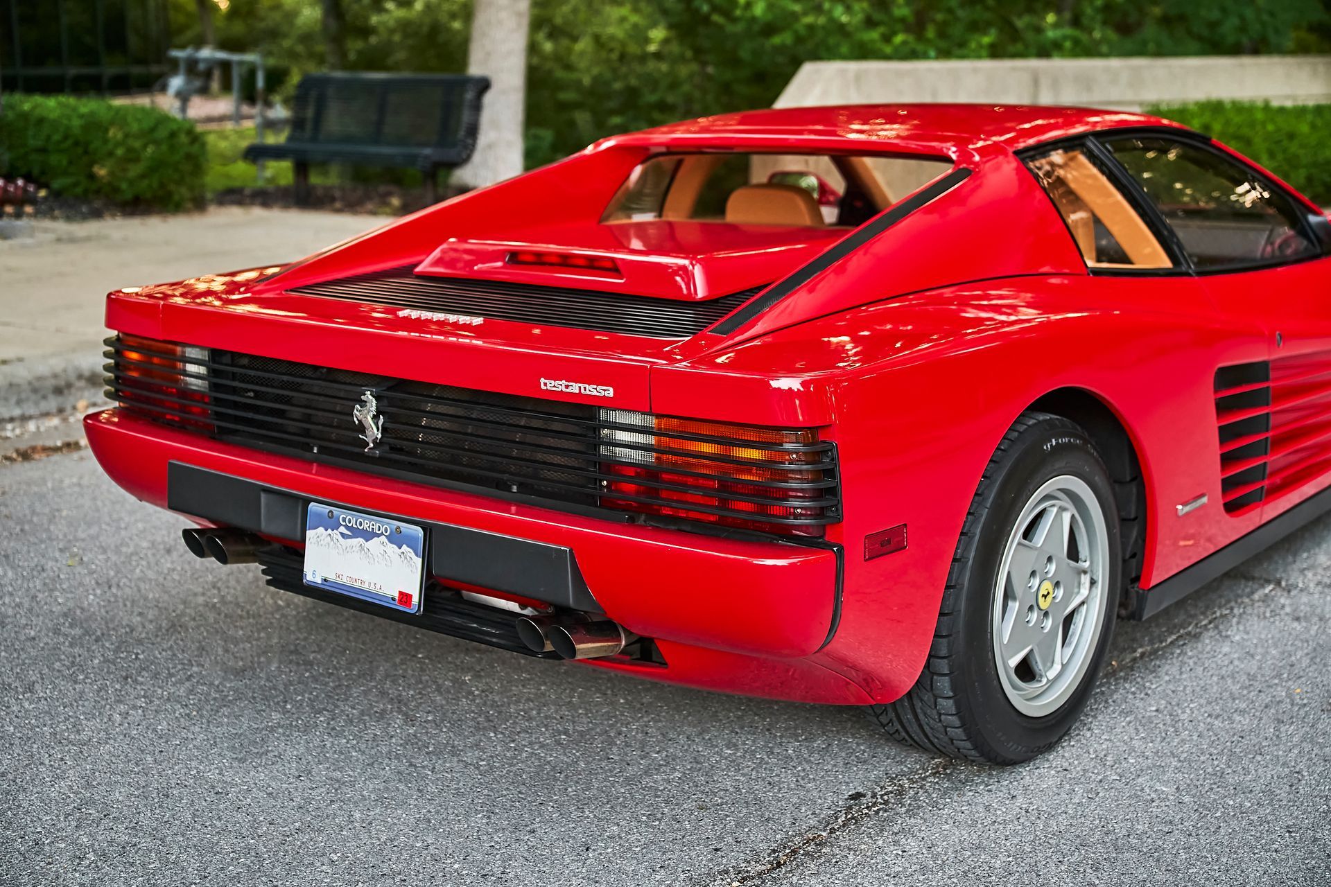 A red ferrari testarossa is parked on the side of the road.