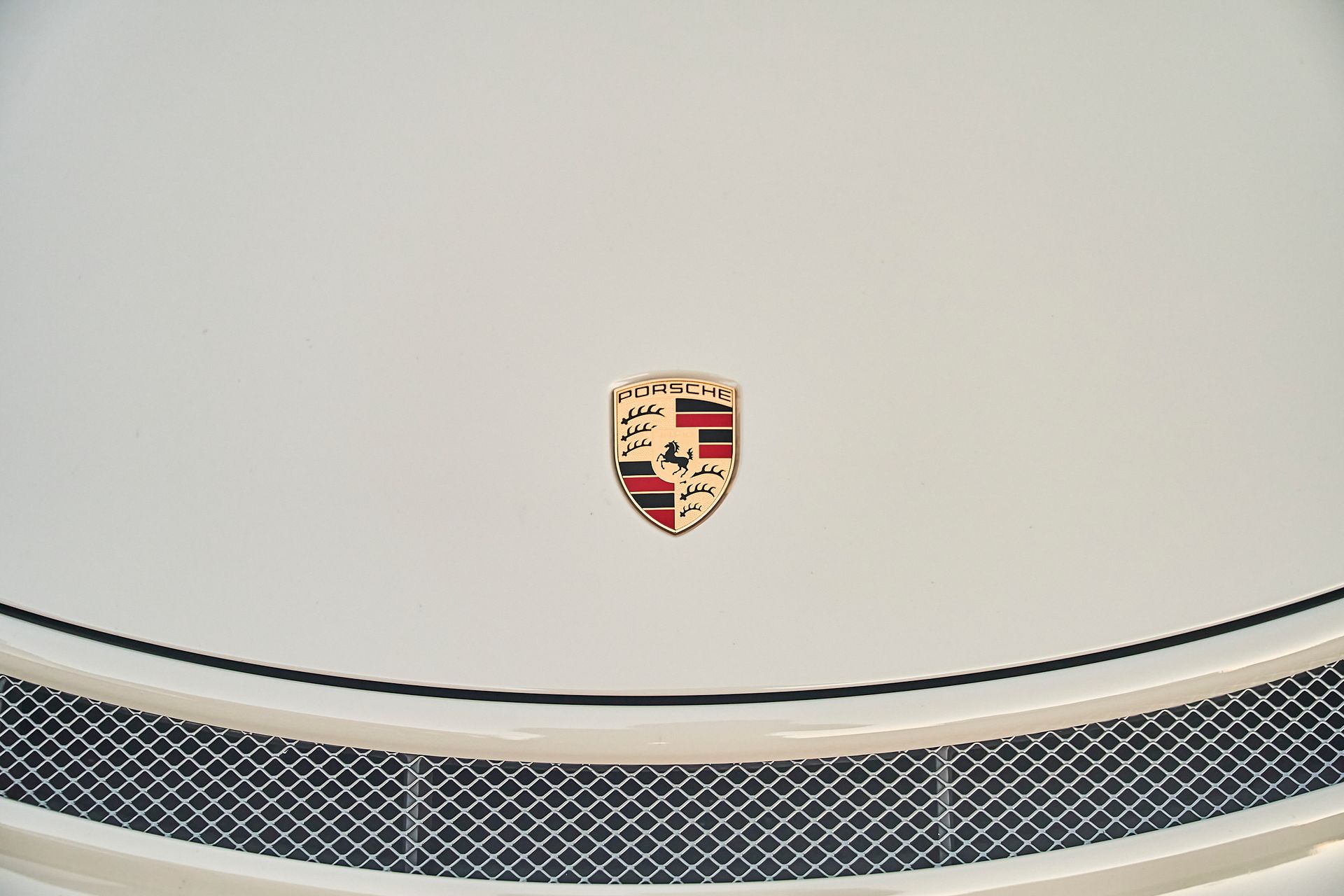 The hood of a white porsche with a shield on it.