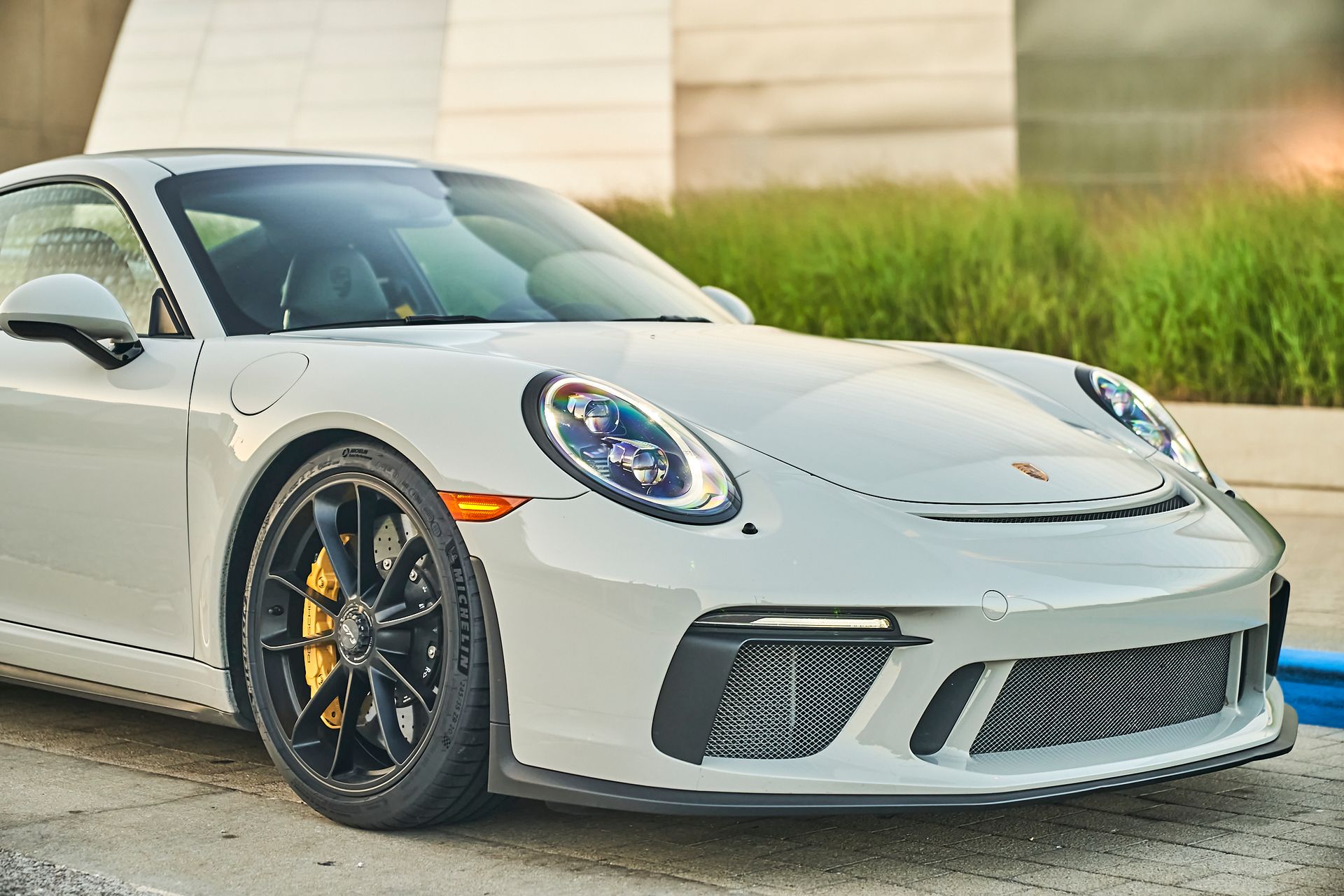 A white porsche 911 gt3 is parked in a parking lot.
