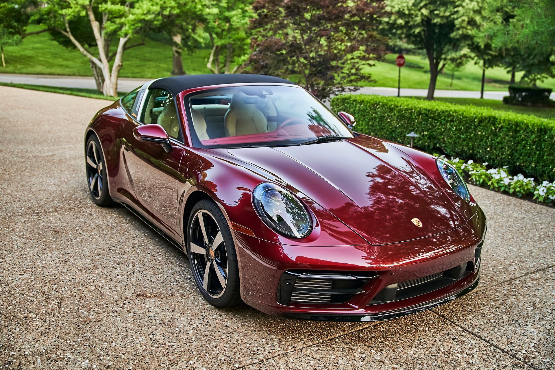 A red porsche targa is parked on a gravel driveway.