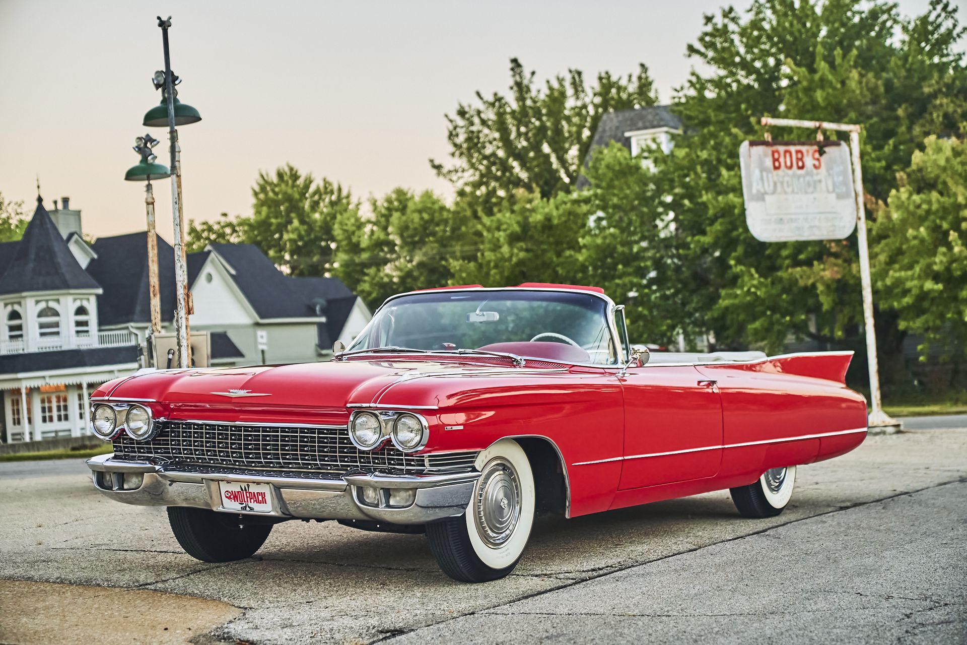 A red cadillac is parked in front of a gas station