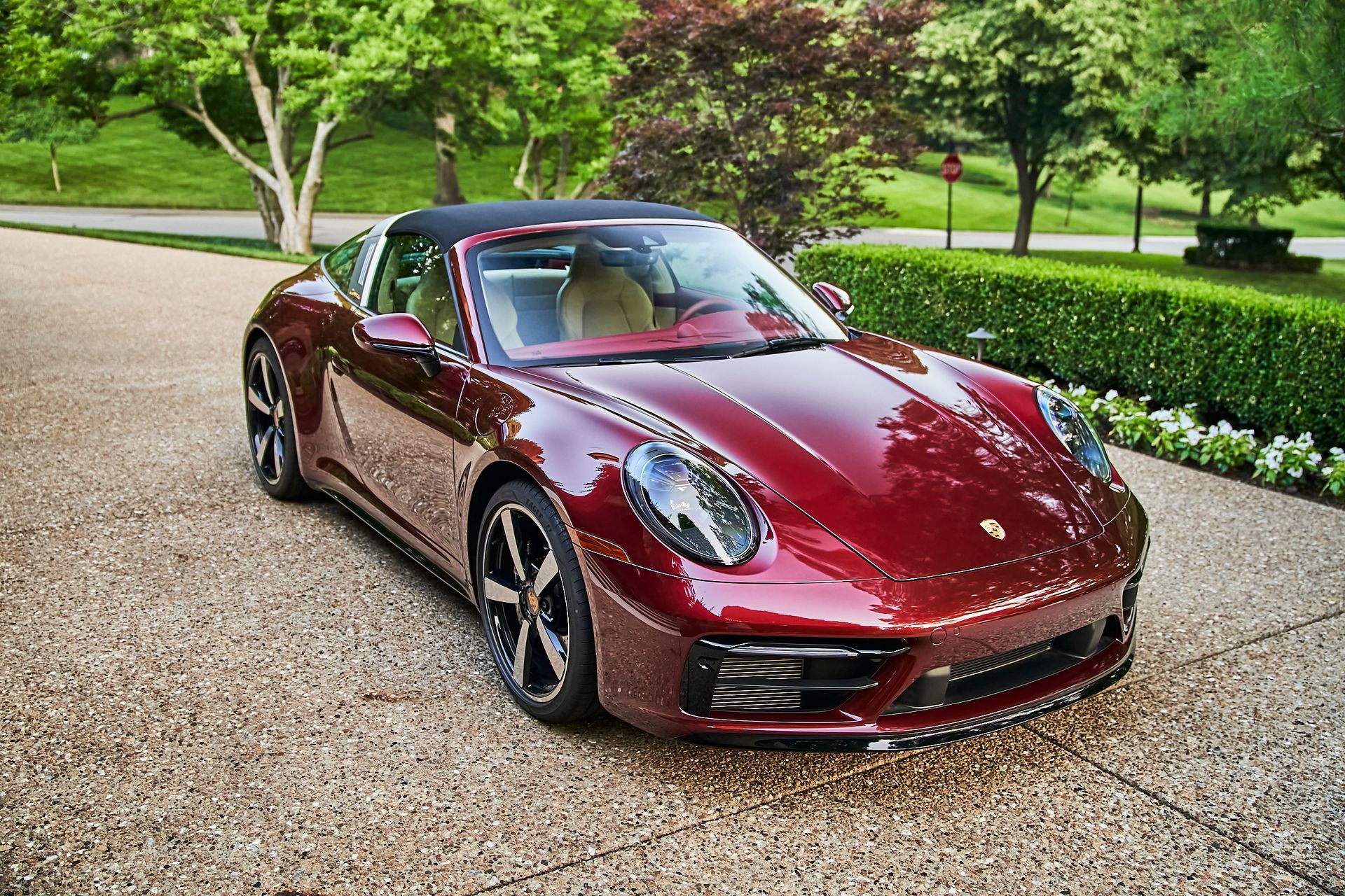 A red porsche targa is parked on a gravel driveway.
