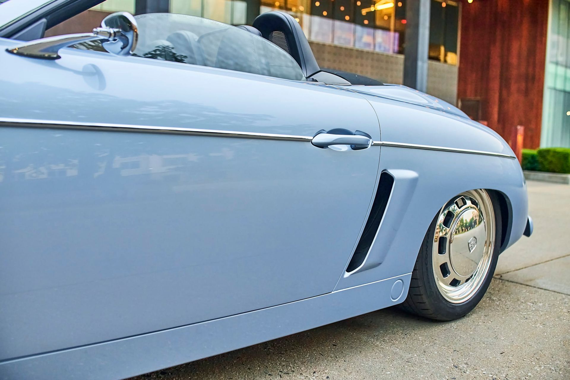 Light blue convertible car parked on a sidewalk. Features chrome accents and custom wheels.