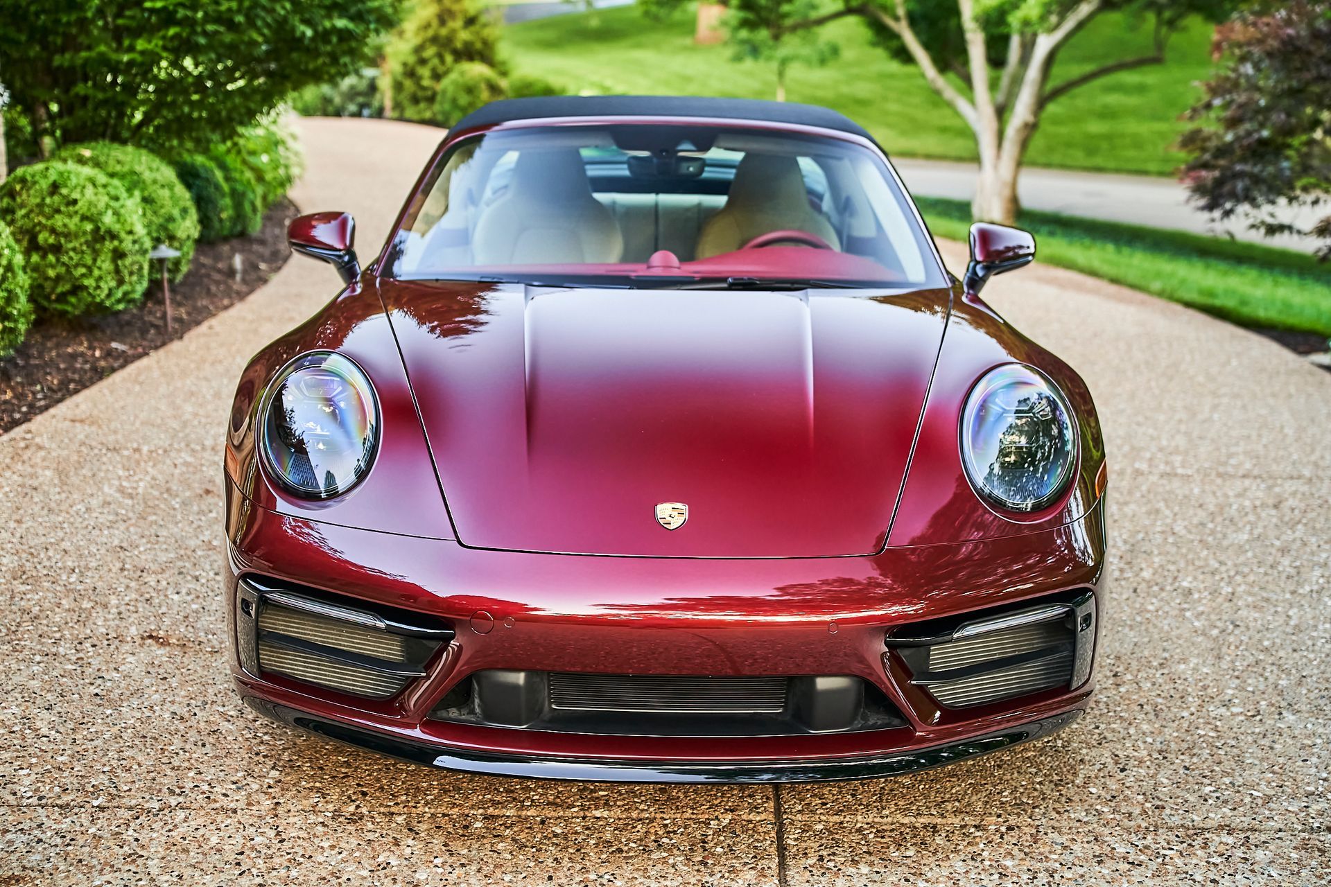 A red sports car is parked on a gravel driveway.