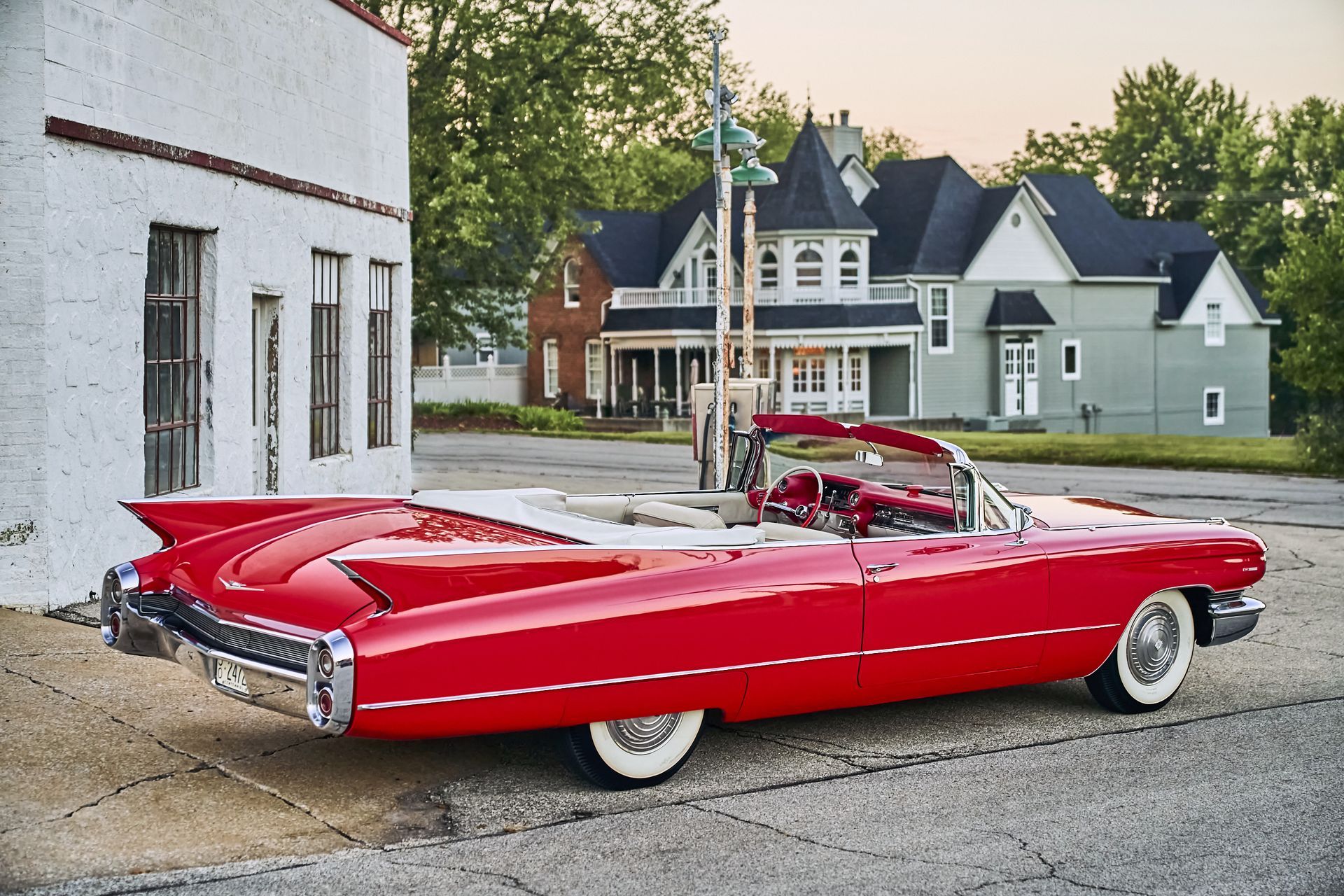 A red cadillac is parked in front of a white building
