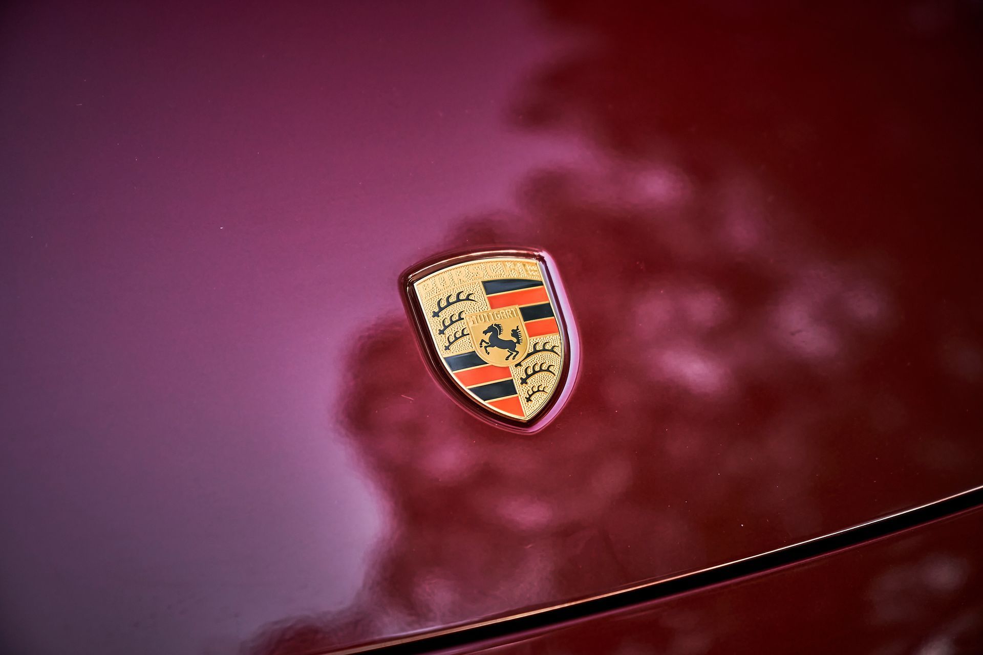 A close up of a porsche emblem on the side of a red car.