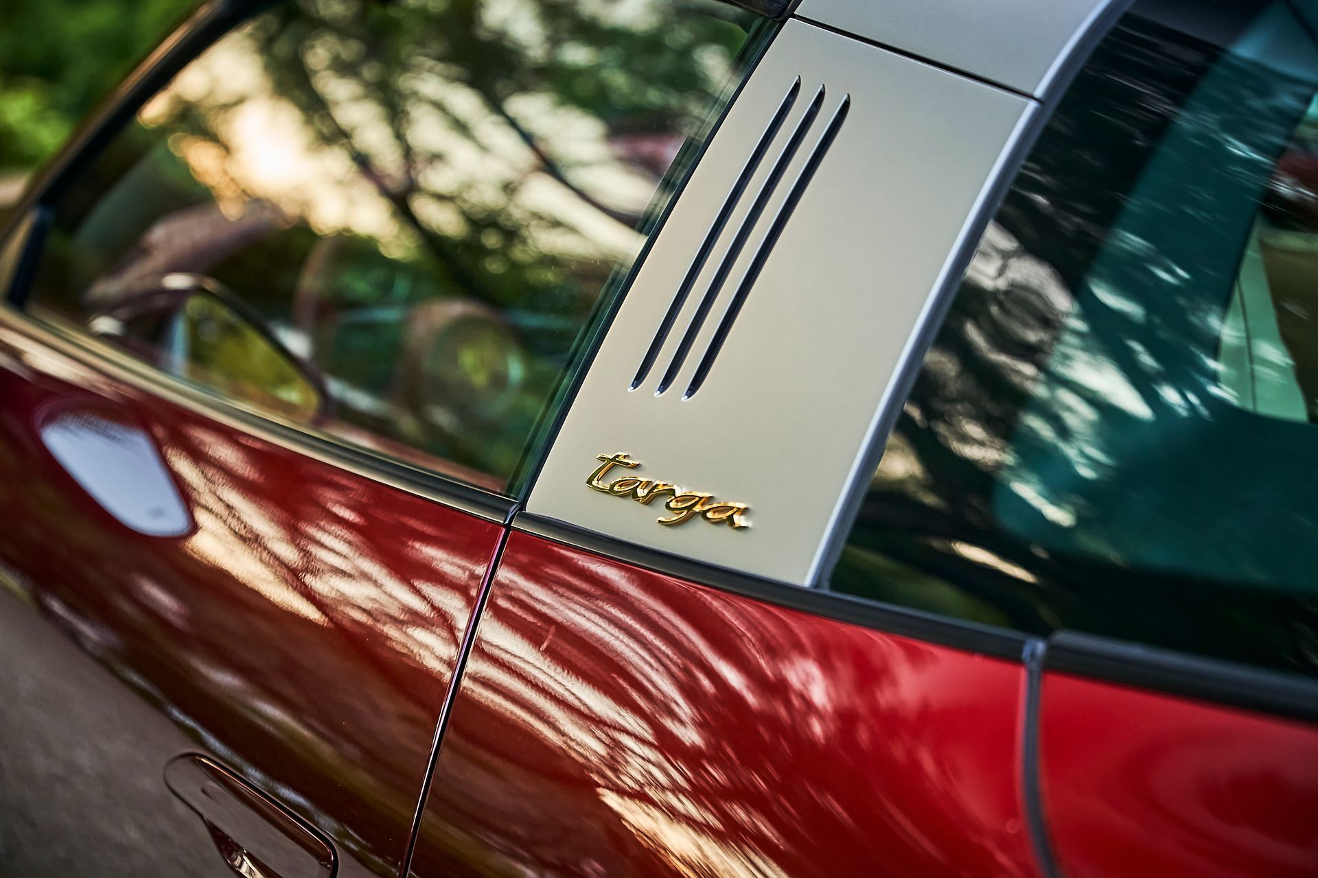 A red porsche targa is parked on the side of the road.