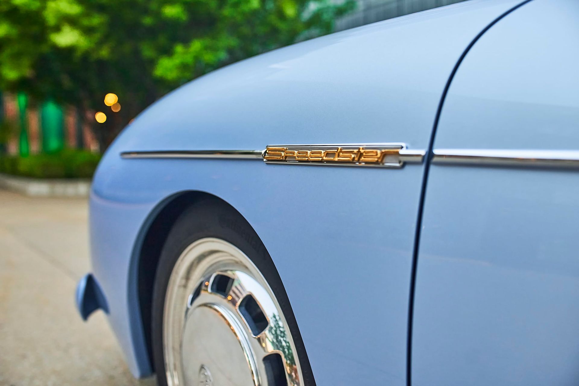 Close-up of a light blue vintage car's side, showcasing the chrome trim and a