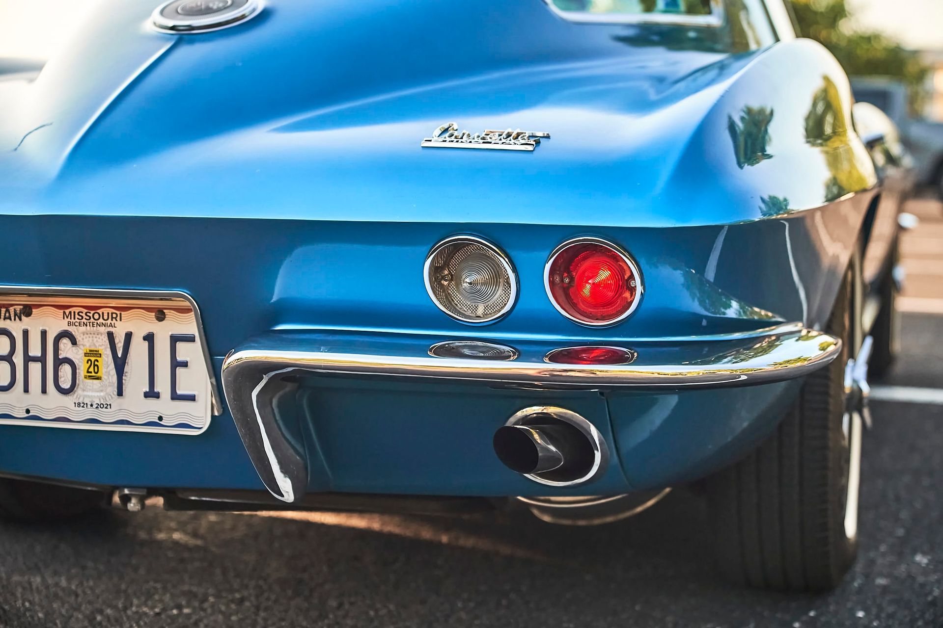 Blue vintage Chevrolet Corvette rear end with chrome accents, round taillights, and license plate.