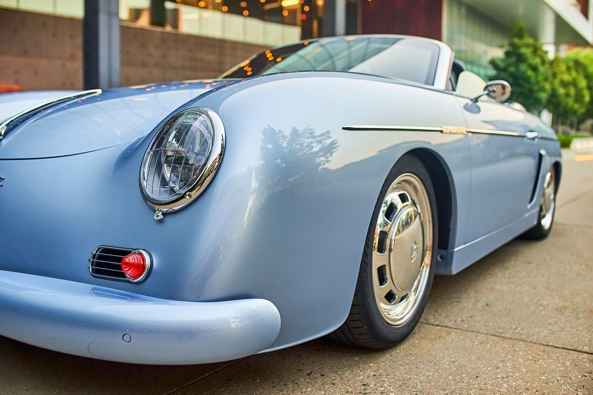 Light blue classic convertible car parked in front of a building. Chrome details and a shiny finish are visible.