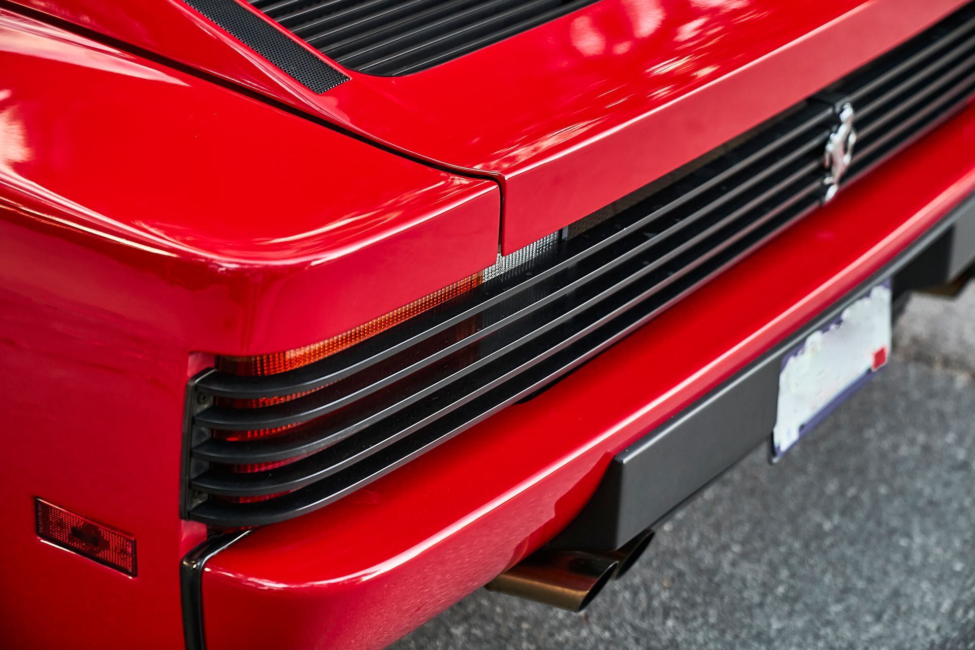 A close up of the front of a red ferrari with a license plate.
