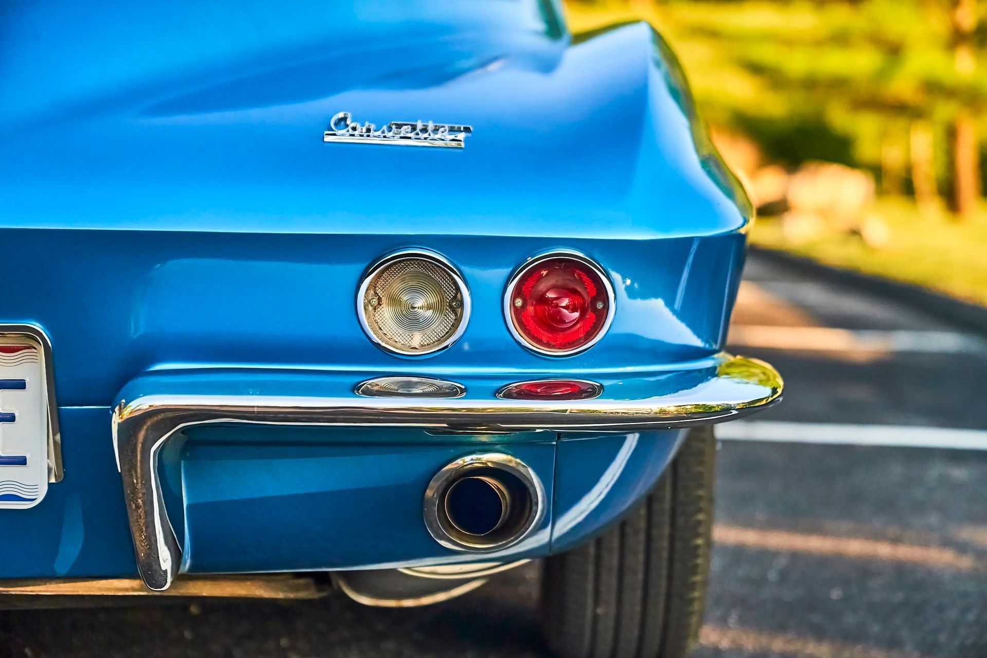 Rear view of a classic blue Corvette with chrome accents and round taillights.