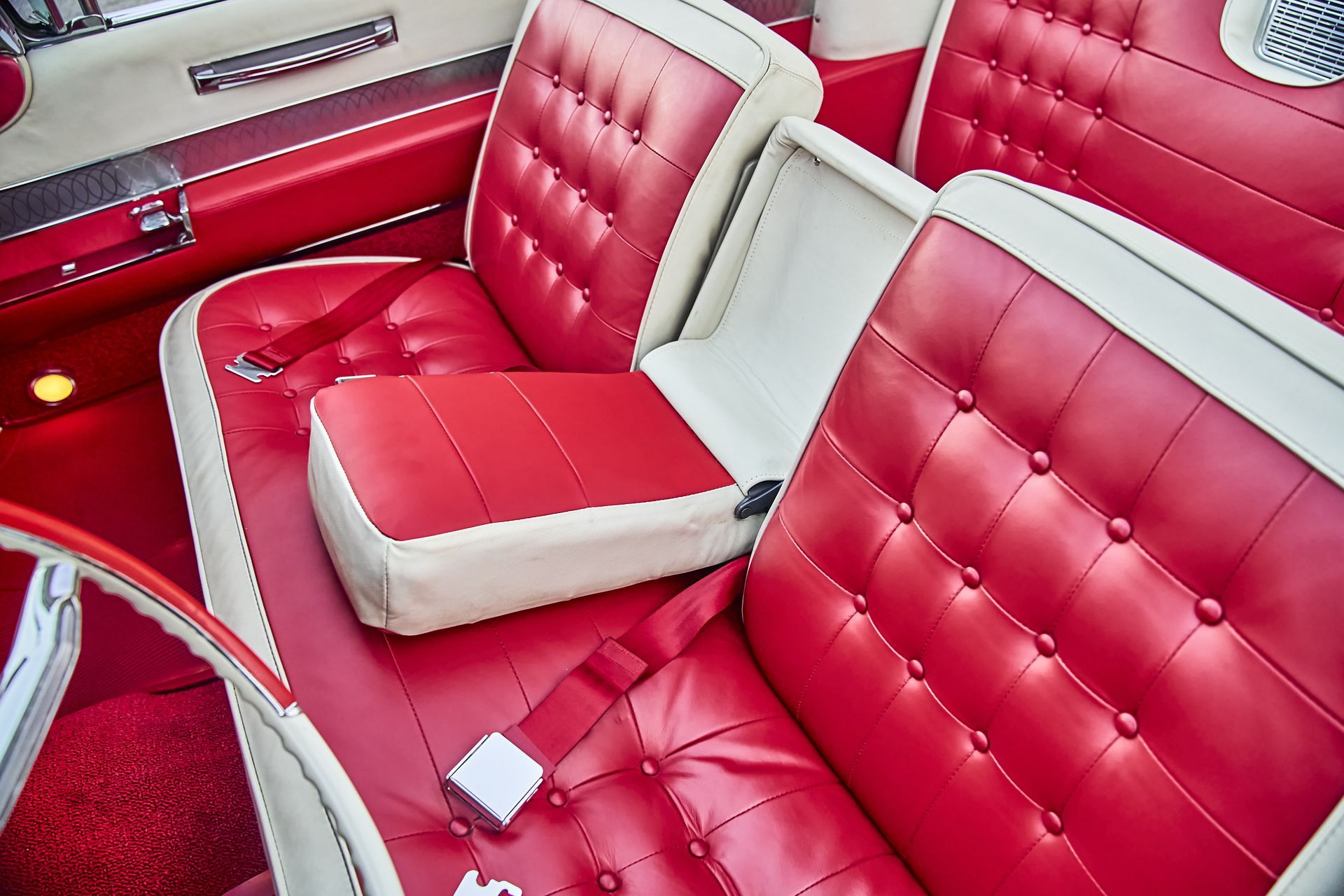 The interior of a red and white car with red seats and a white seat belt.