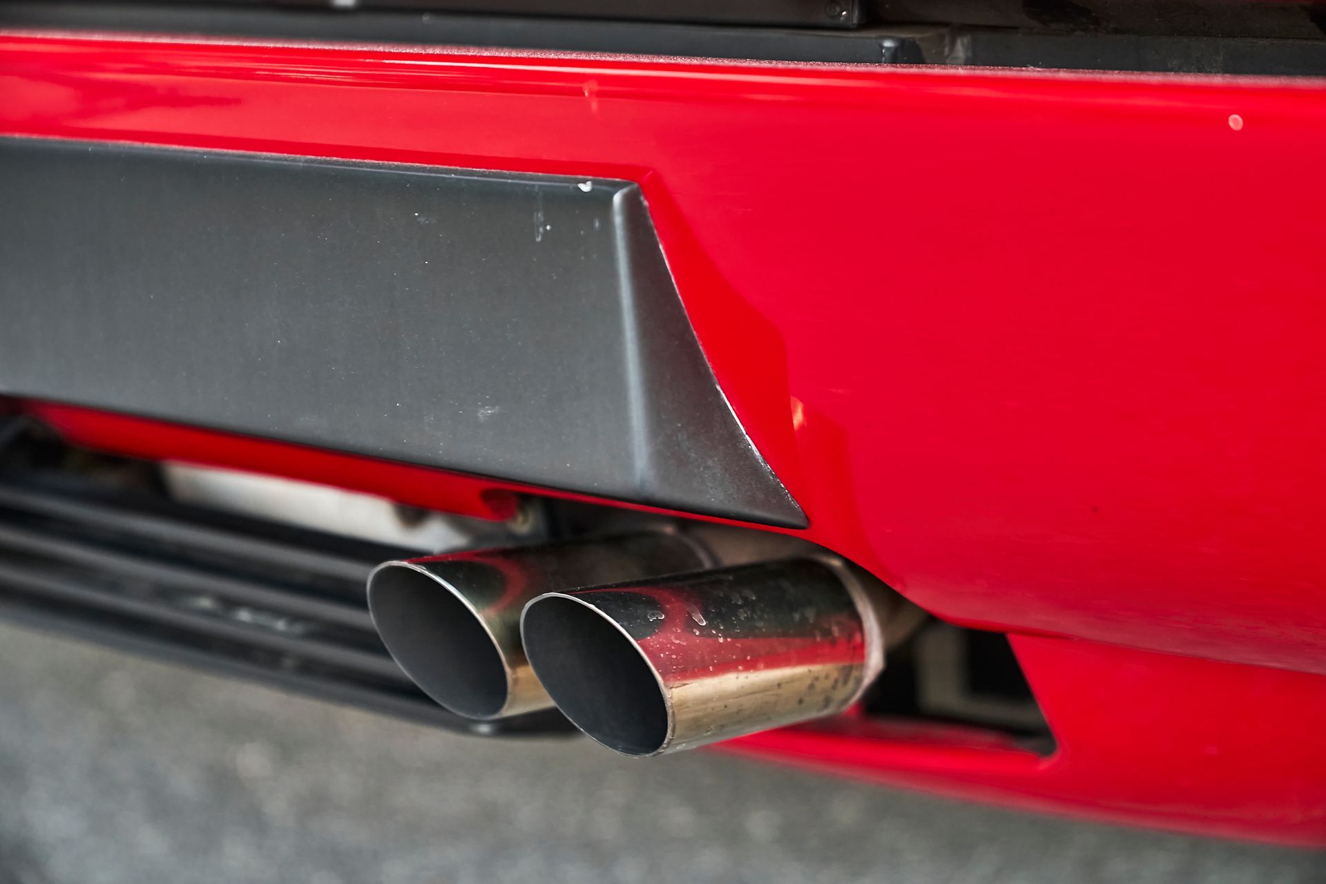 A close up of a red car 's exhaust pipes.