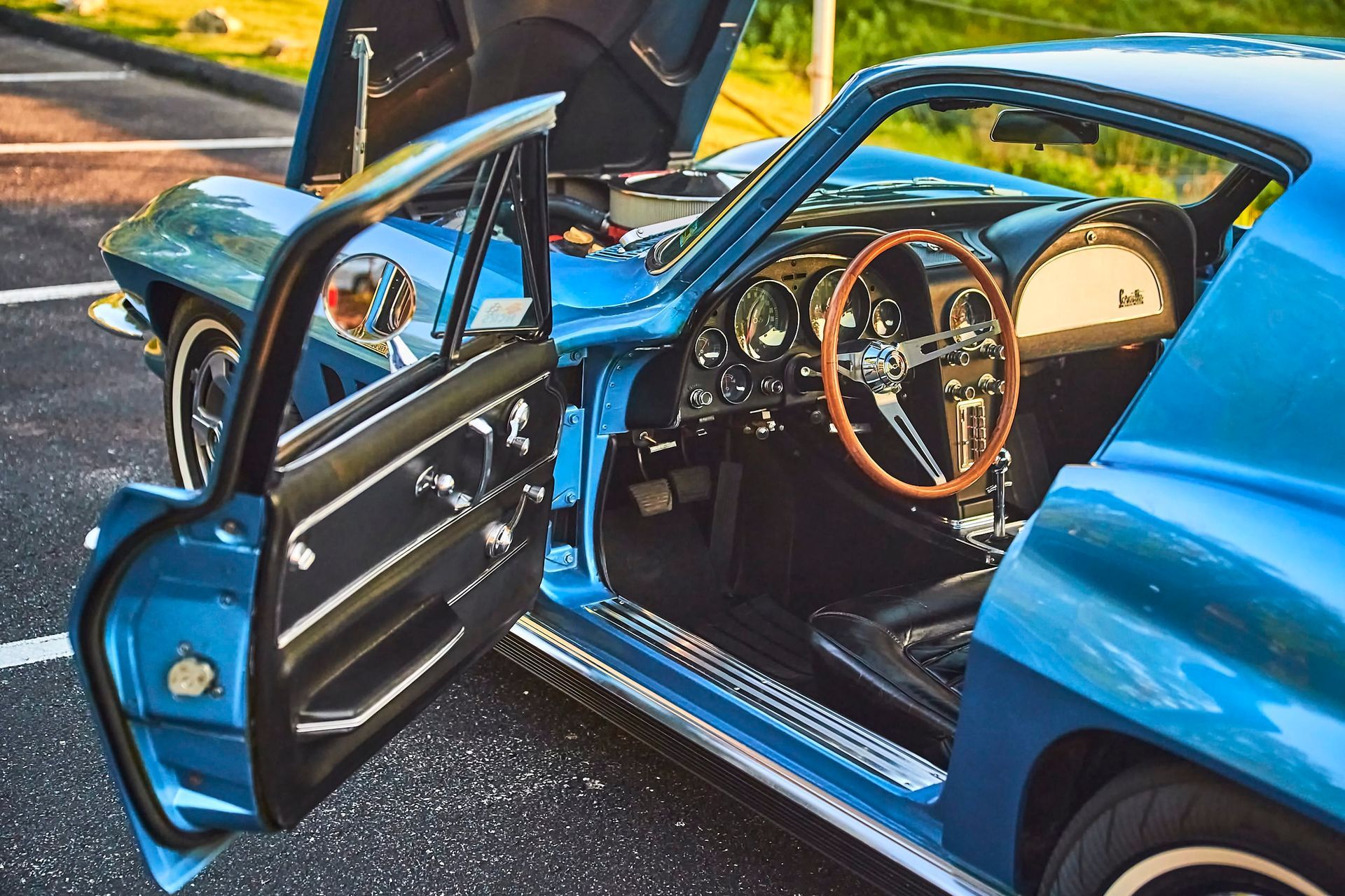 Blue classic Corvette with the door and hood open, showing interior and engine bay.