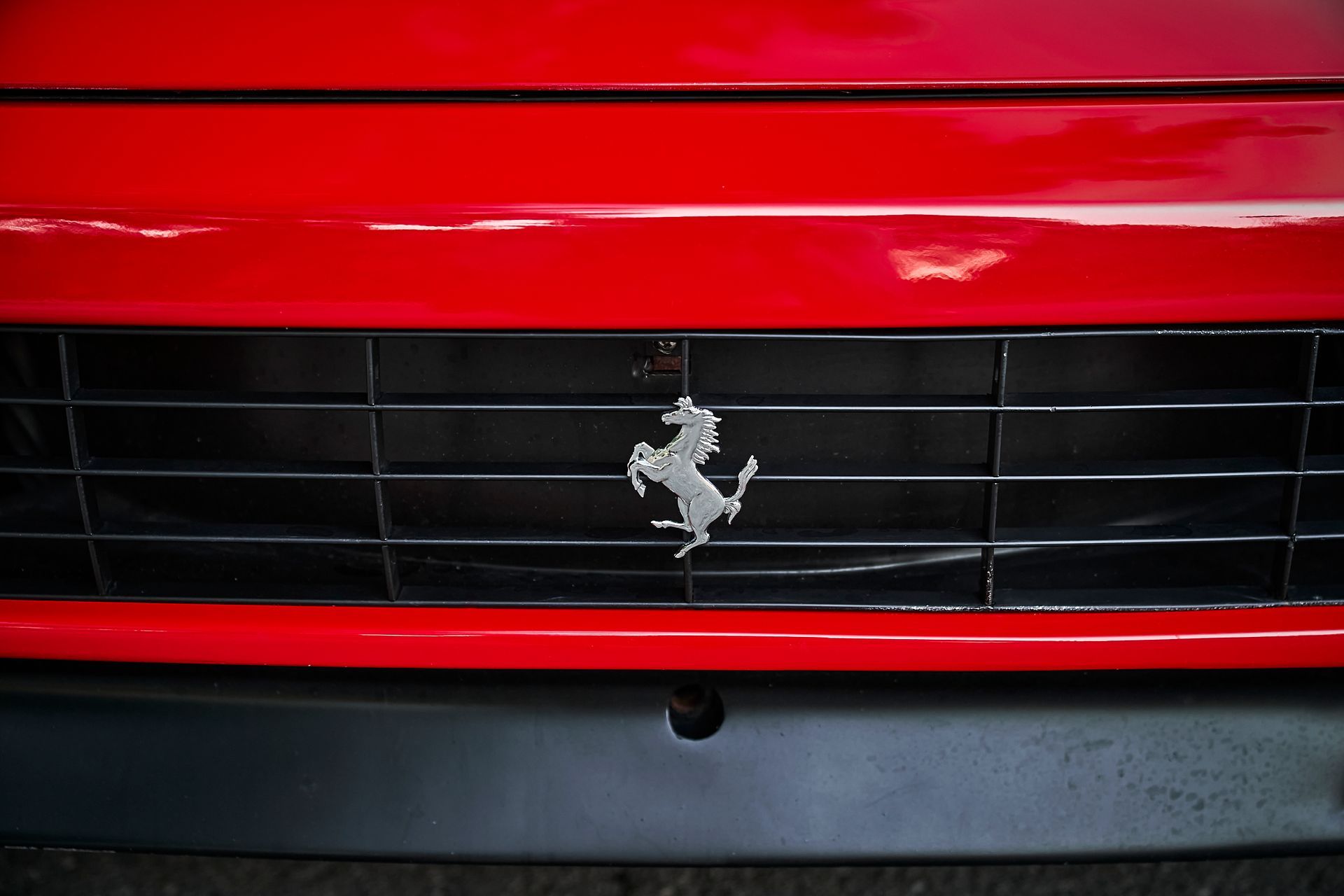 The front grille of a red ferrari with a horse on it.