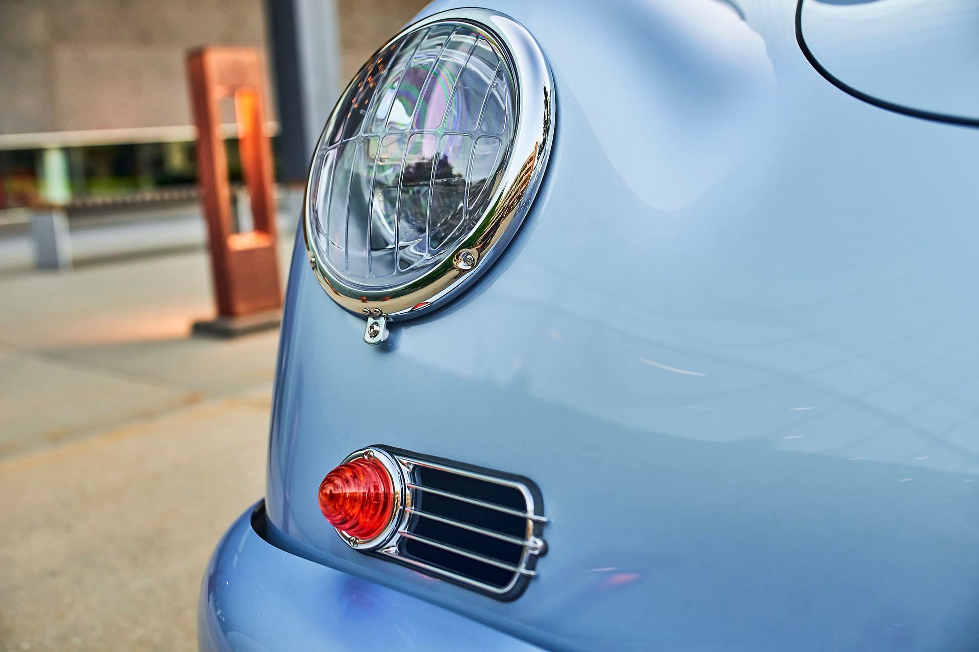 Close-up of a light blue vintage Porsche car's front headlight and side marker light.