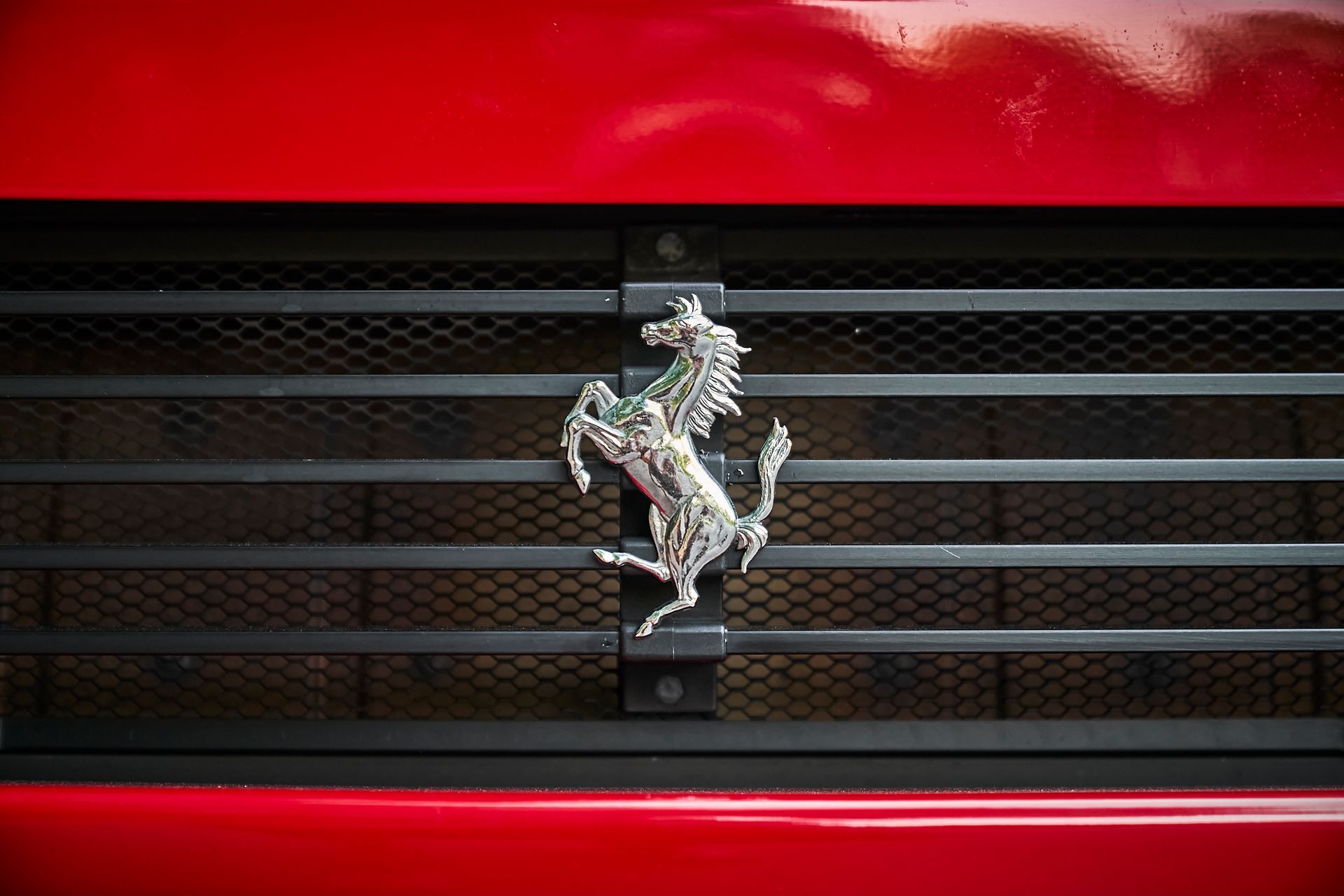 The front grille of a red ferrari with a horse on it.